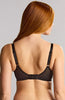 A woman shown from the back wearing a black underwire bra with wide shoulder straps and a center hook-and-eye closure, against a plain light gray studio background.