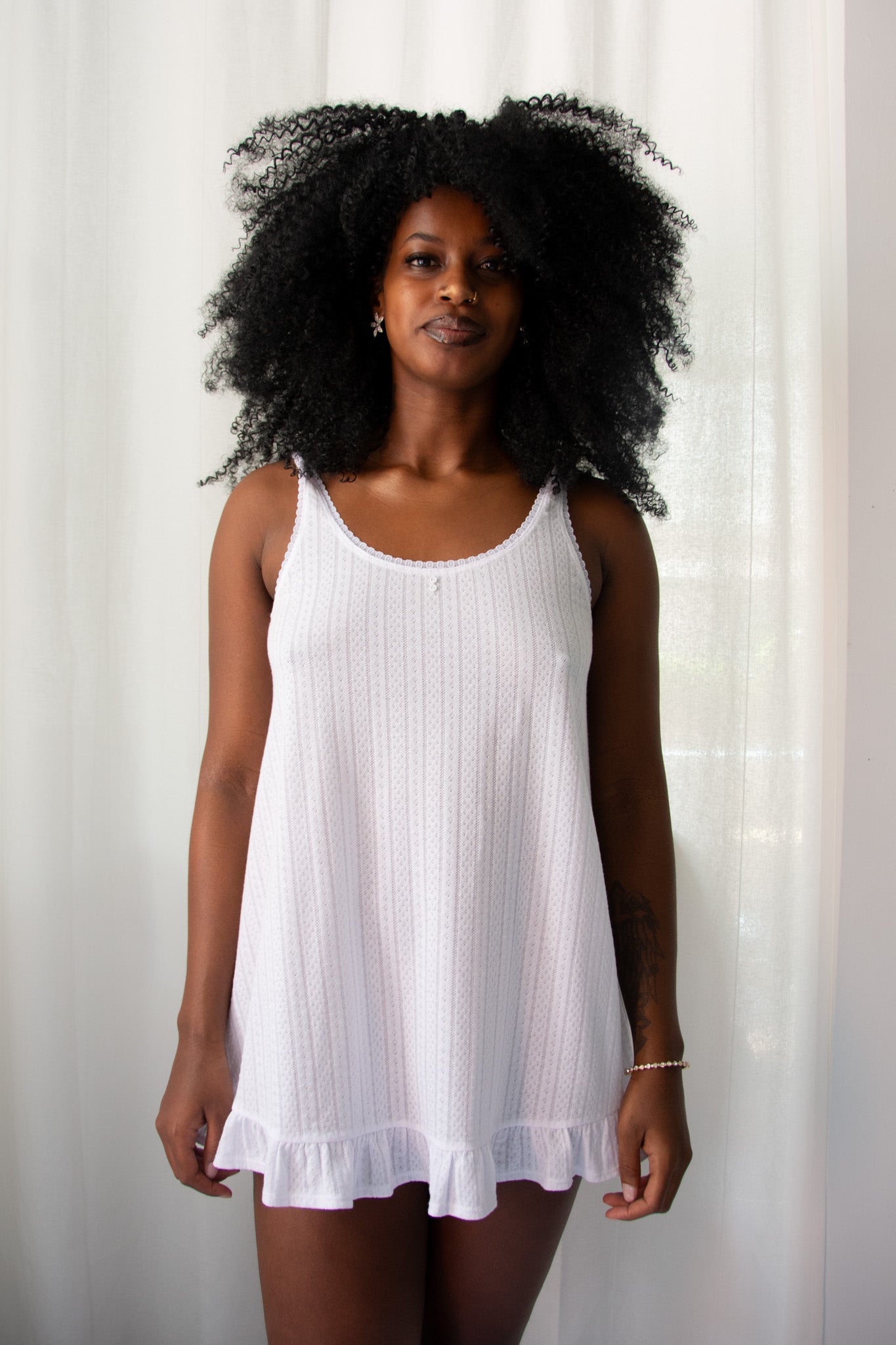 Woman wearing a white sleeveless dress against a plain background