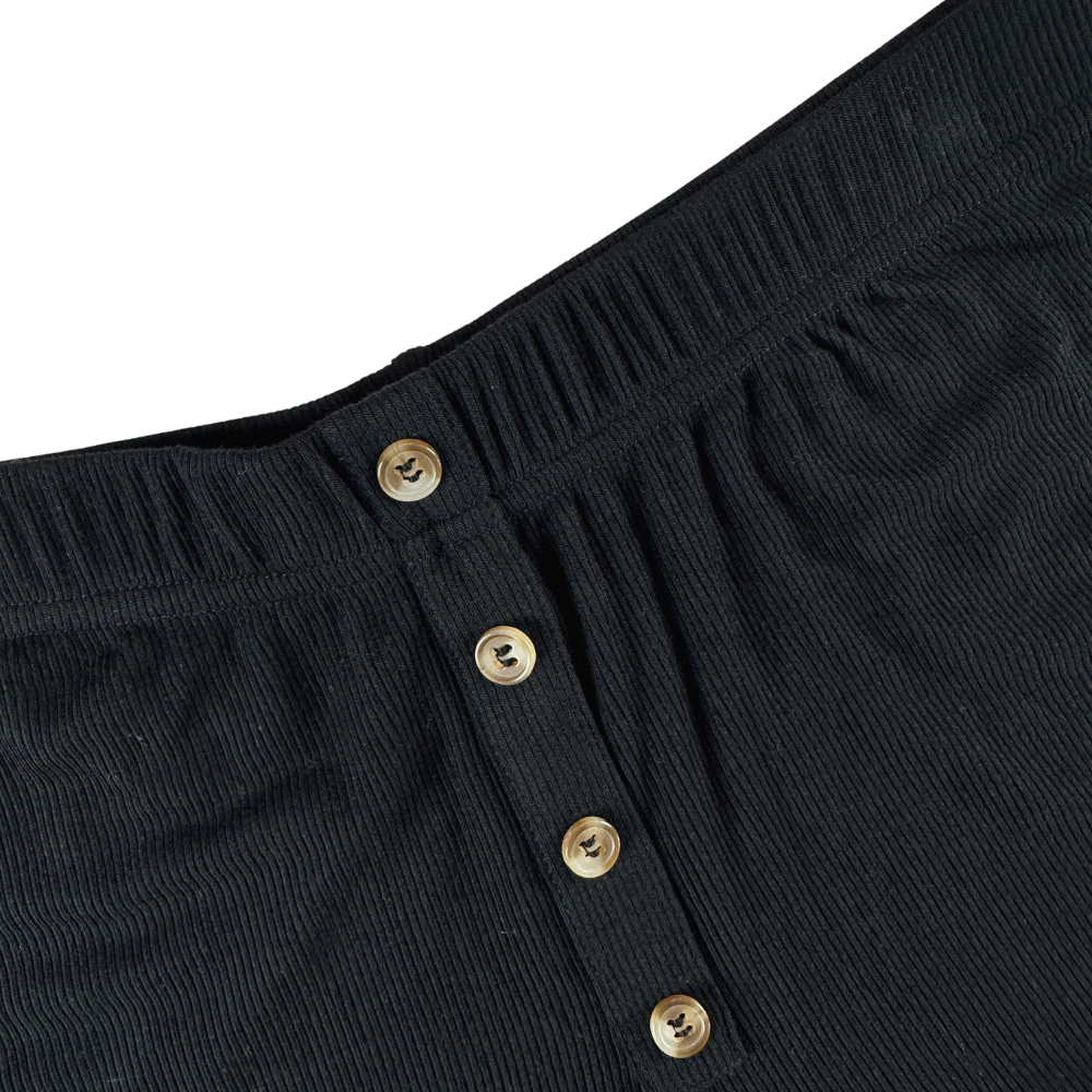 Close-up of black pants with gold buttons on a white background