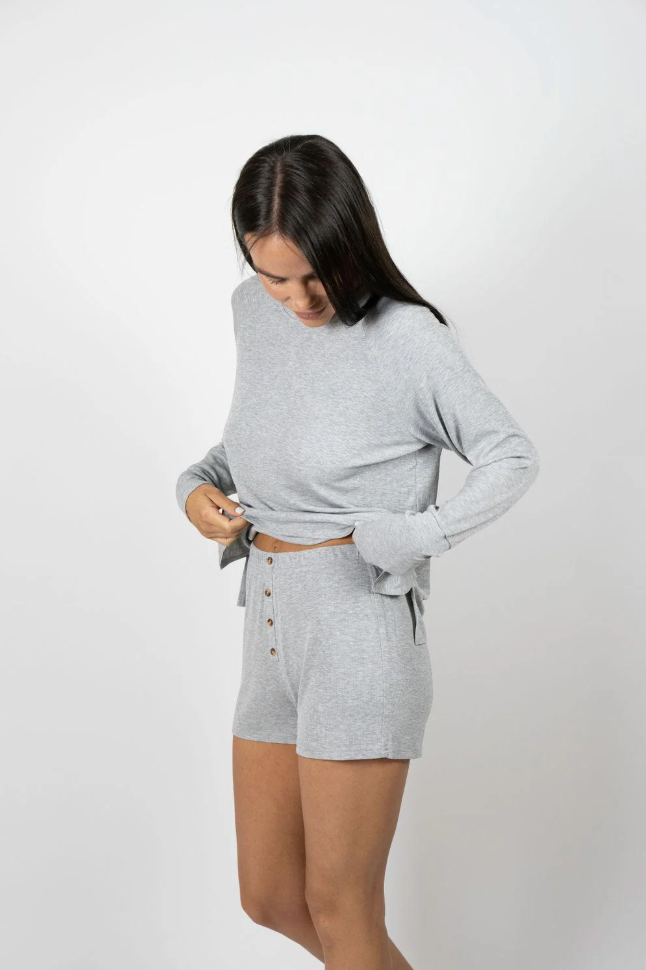 Woman wearing grey pajamas against a white background 
