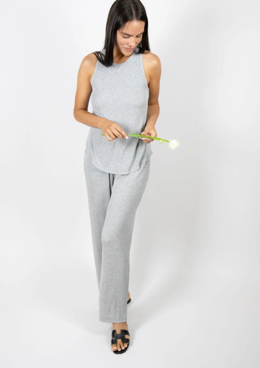 Woman in gray outfit holding a green object against a white background