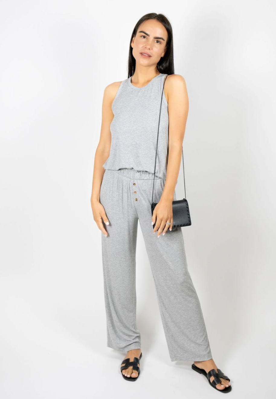 Woman wearing a gray jumpsuit with a plain white background