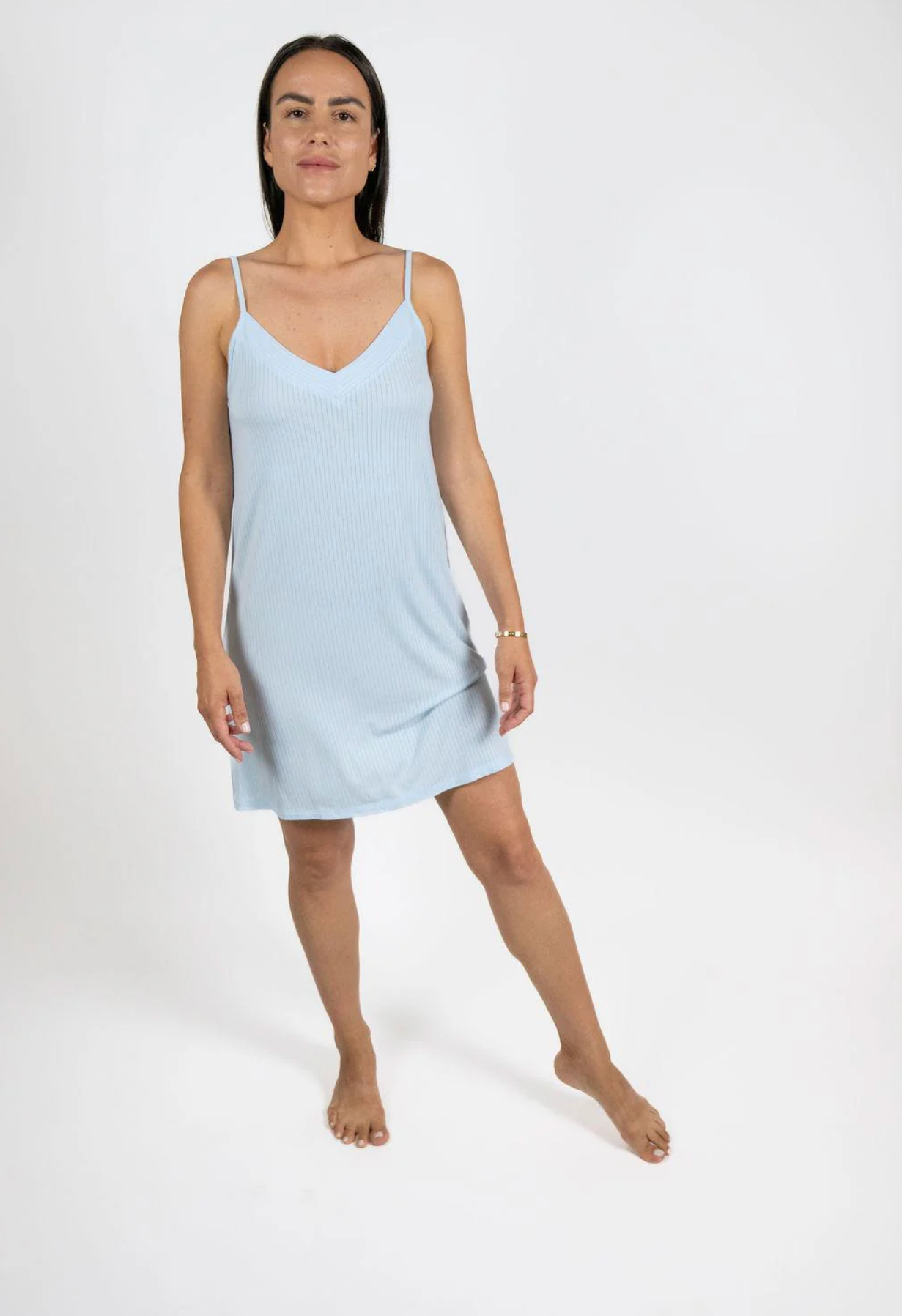 Woman wearing a light blue slip dress on a white background