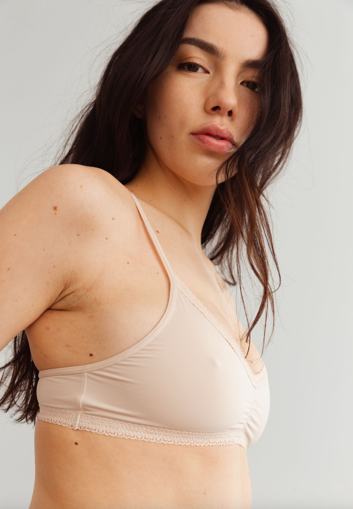 person wearing beige bralette against a white background