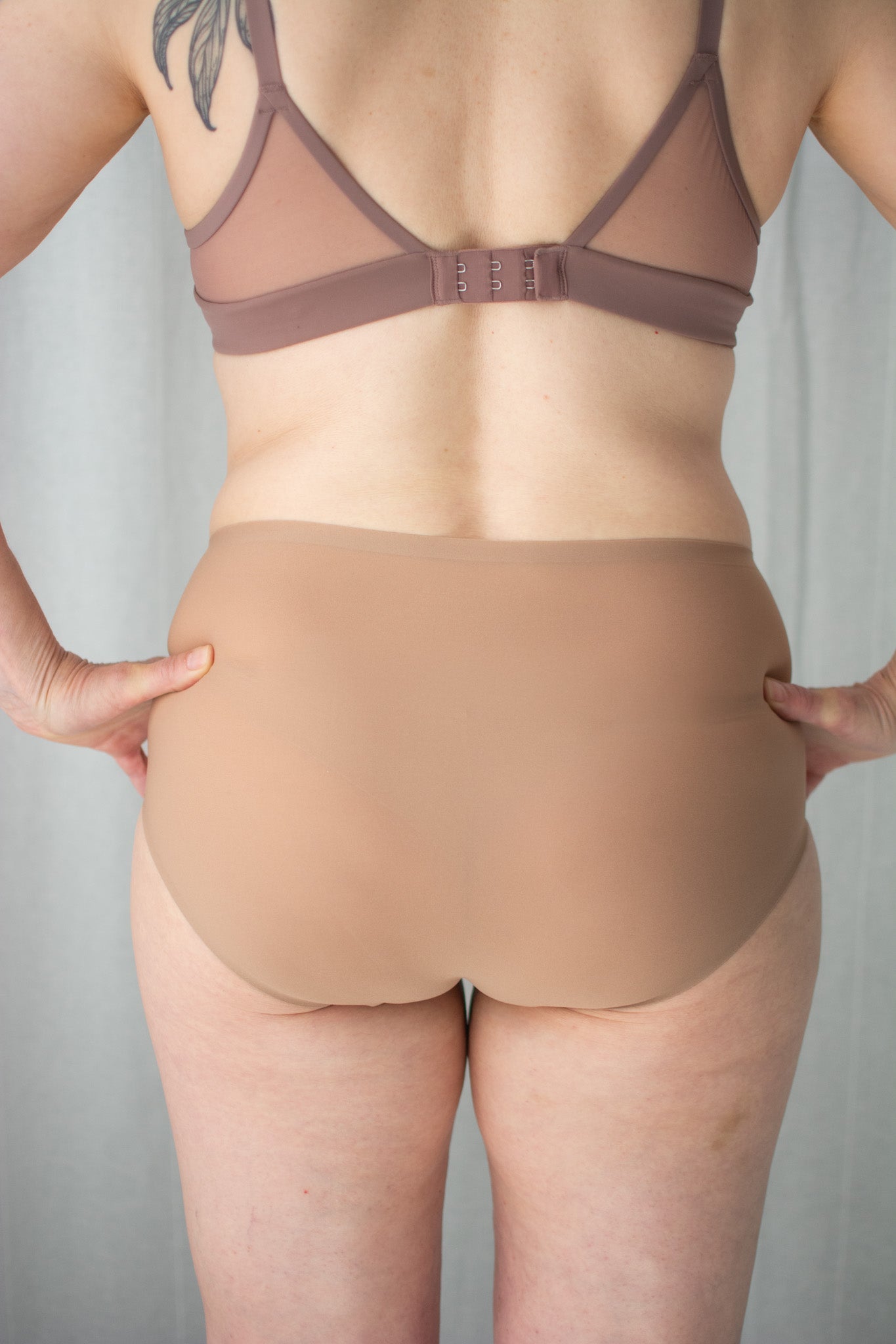 Person wearing a beige bra and panties set against a neutral background