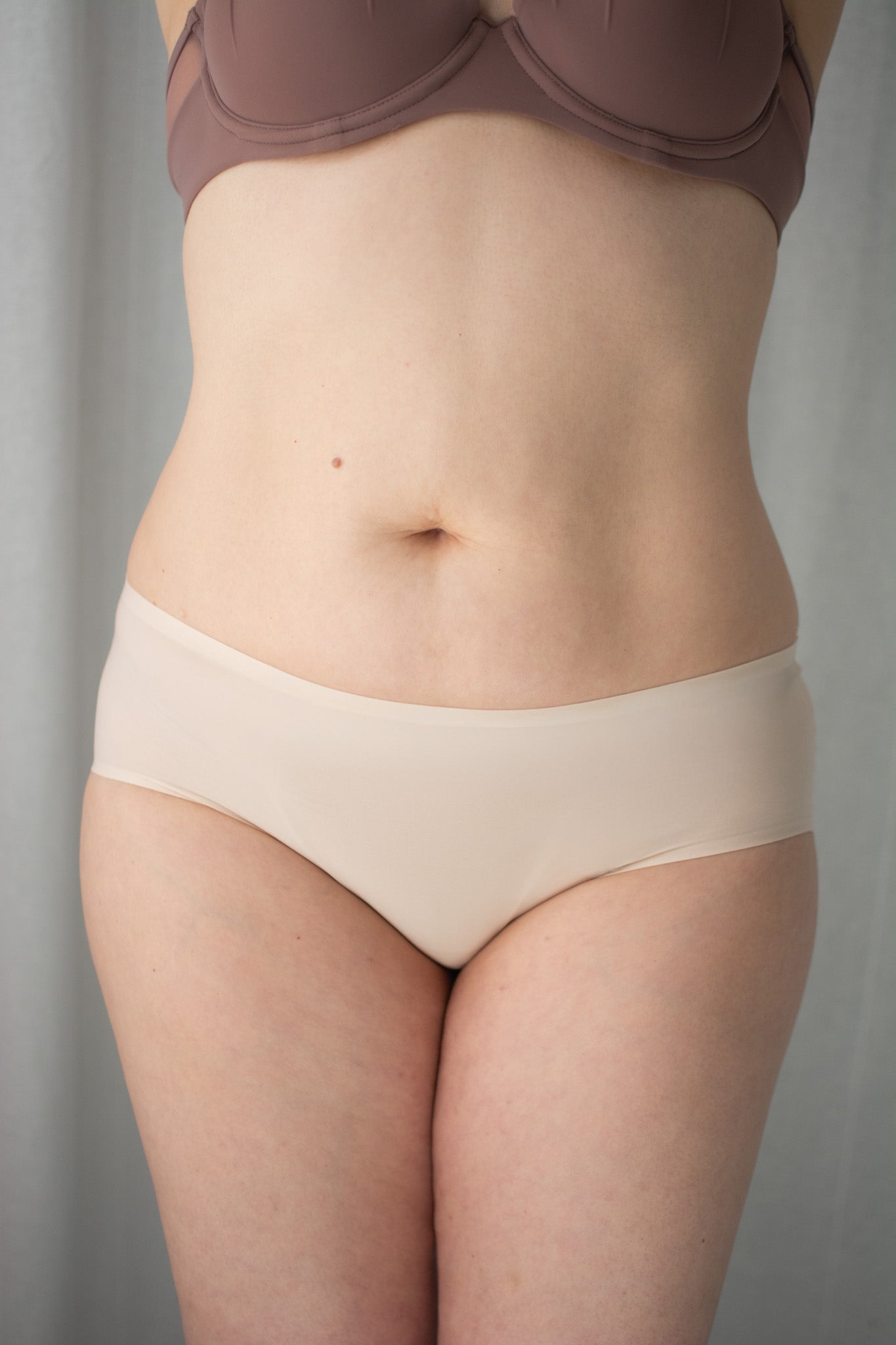 Person wearing a beige underwear set against a plain background