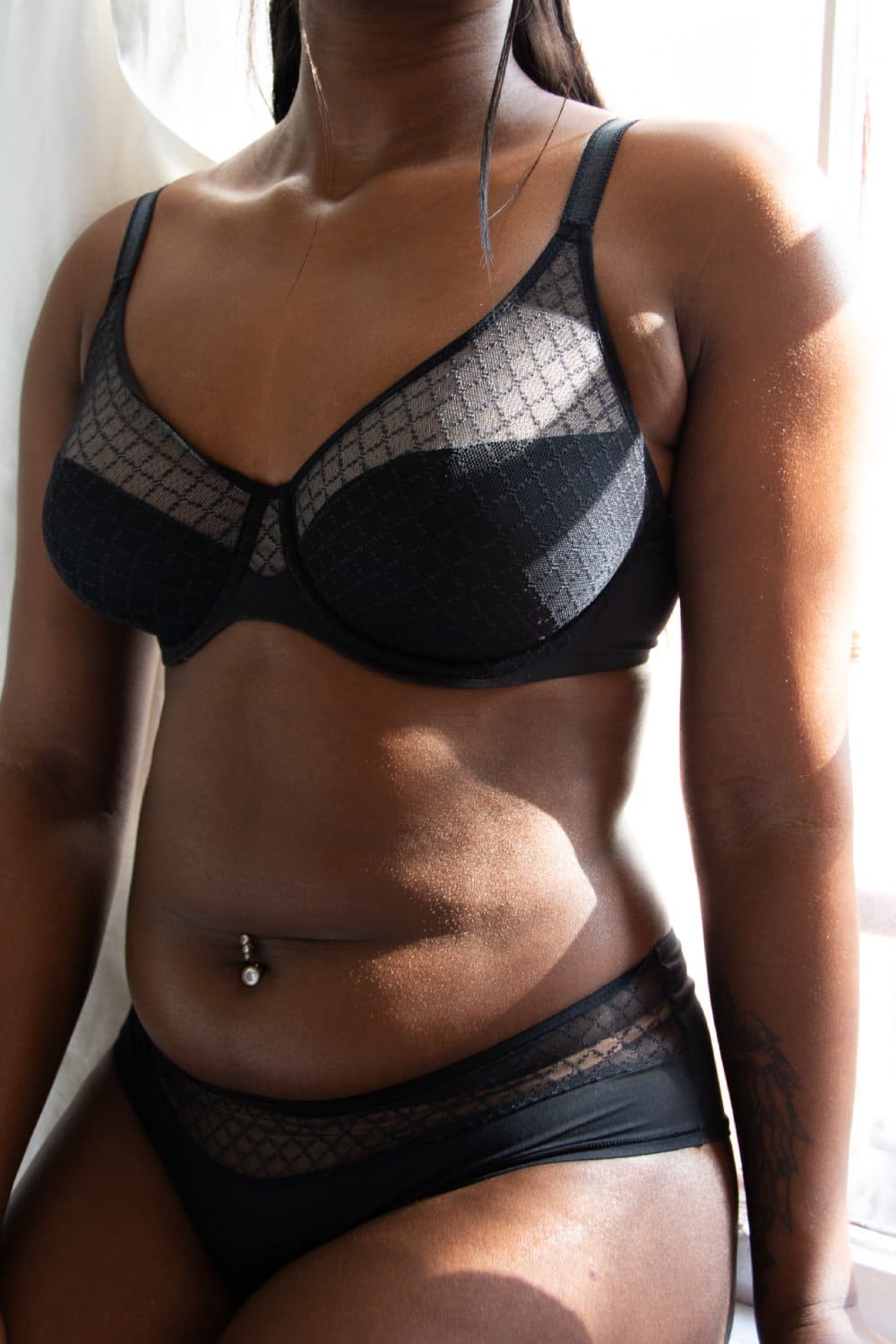 Chantelle norah chic comfort underwire bra in black, front view on a model, close-up, model sitting on a window.