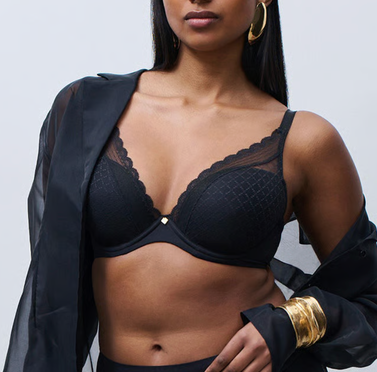Woman wearing a black bralette with a plain background