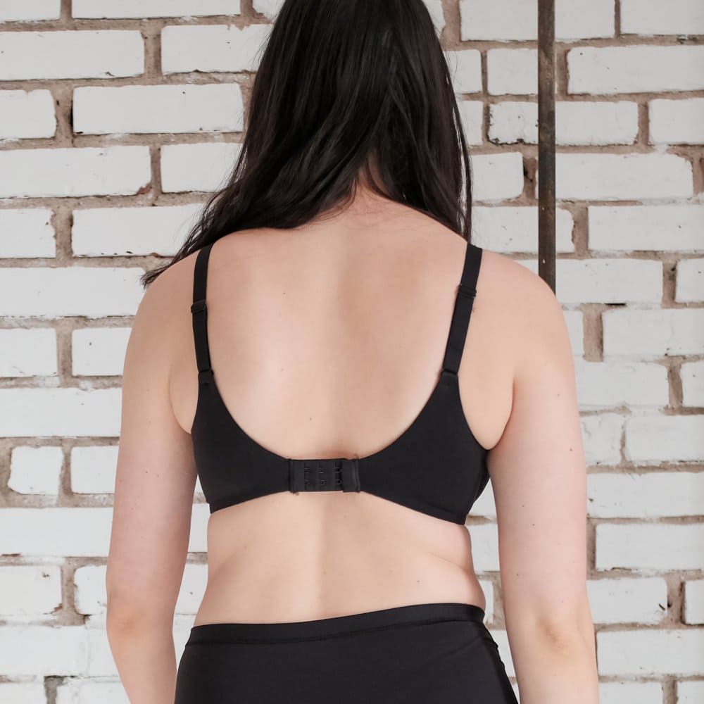 Chantelle norah comfort underwire bra in black, back view on a model, close-up, brick wall background.
