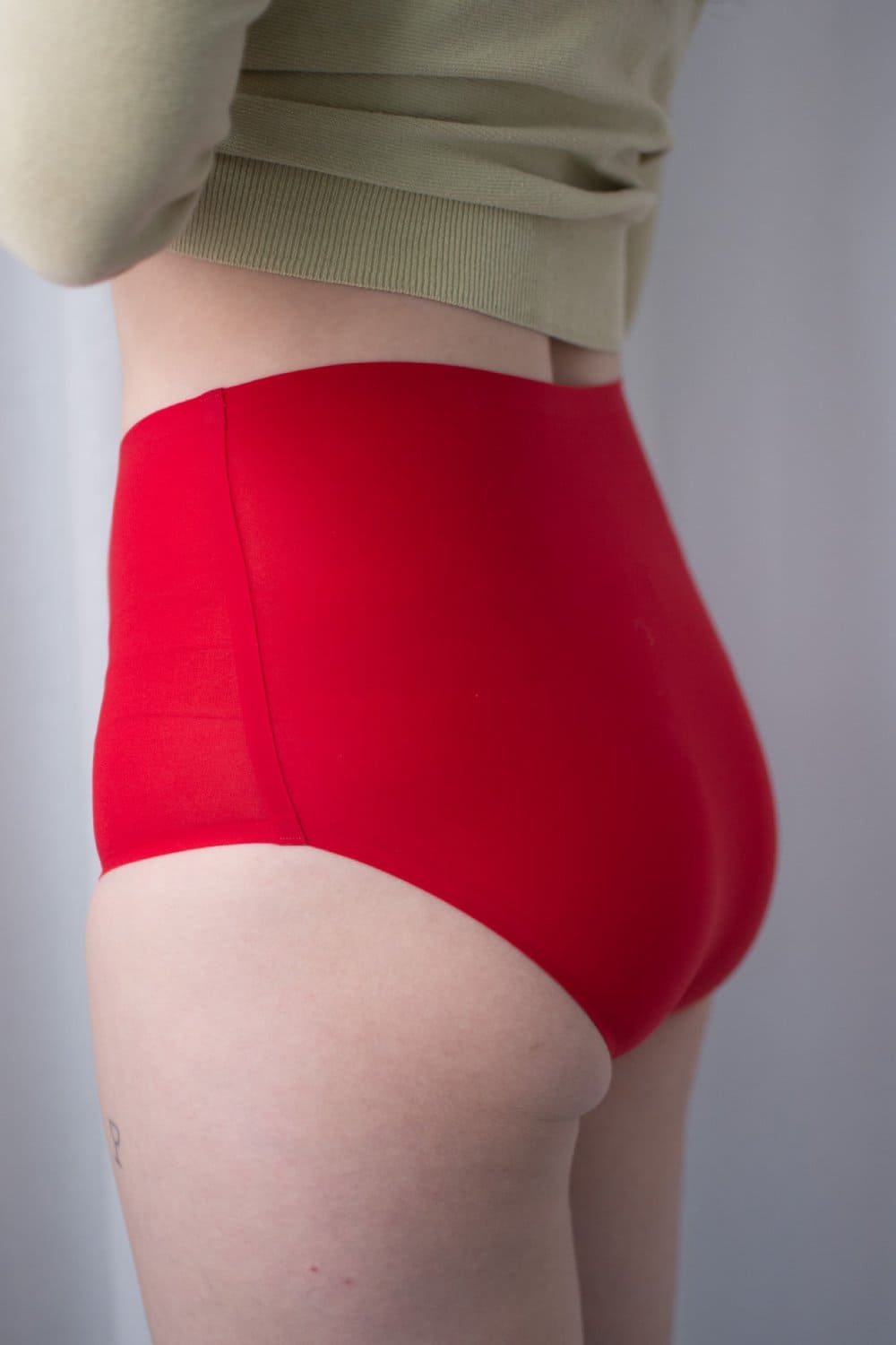 Chantelle soft stretch high rise brief in poppy red, side view on a model, close-up.