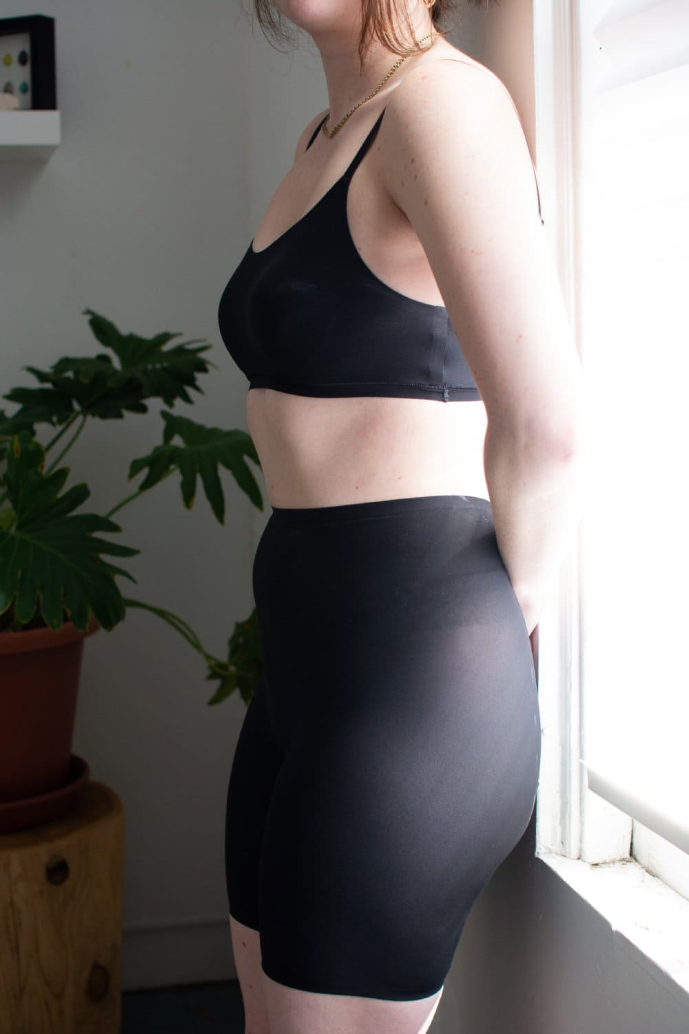 Chantelle soft stretch mid-thigh short in black, side close-up on a model.