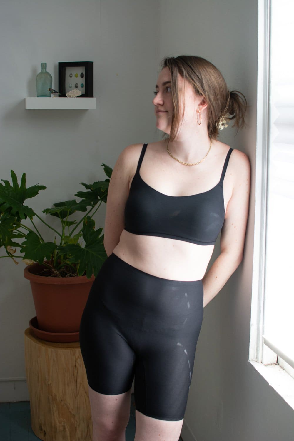 Chantelle soft stretch mid-thigh short in black, front view on a model, leaning against a wall.