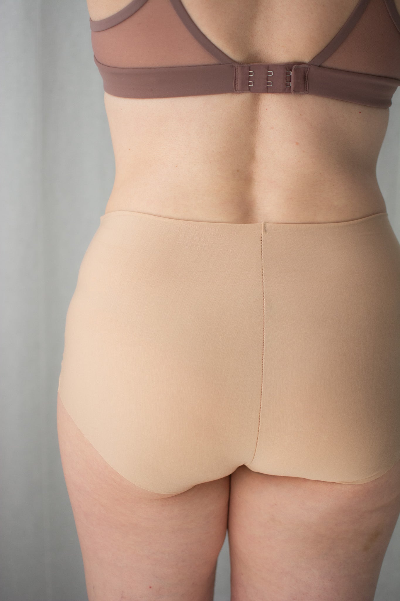 Beige shapewear with a brown bra on a neutral background