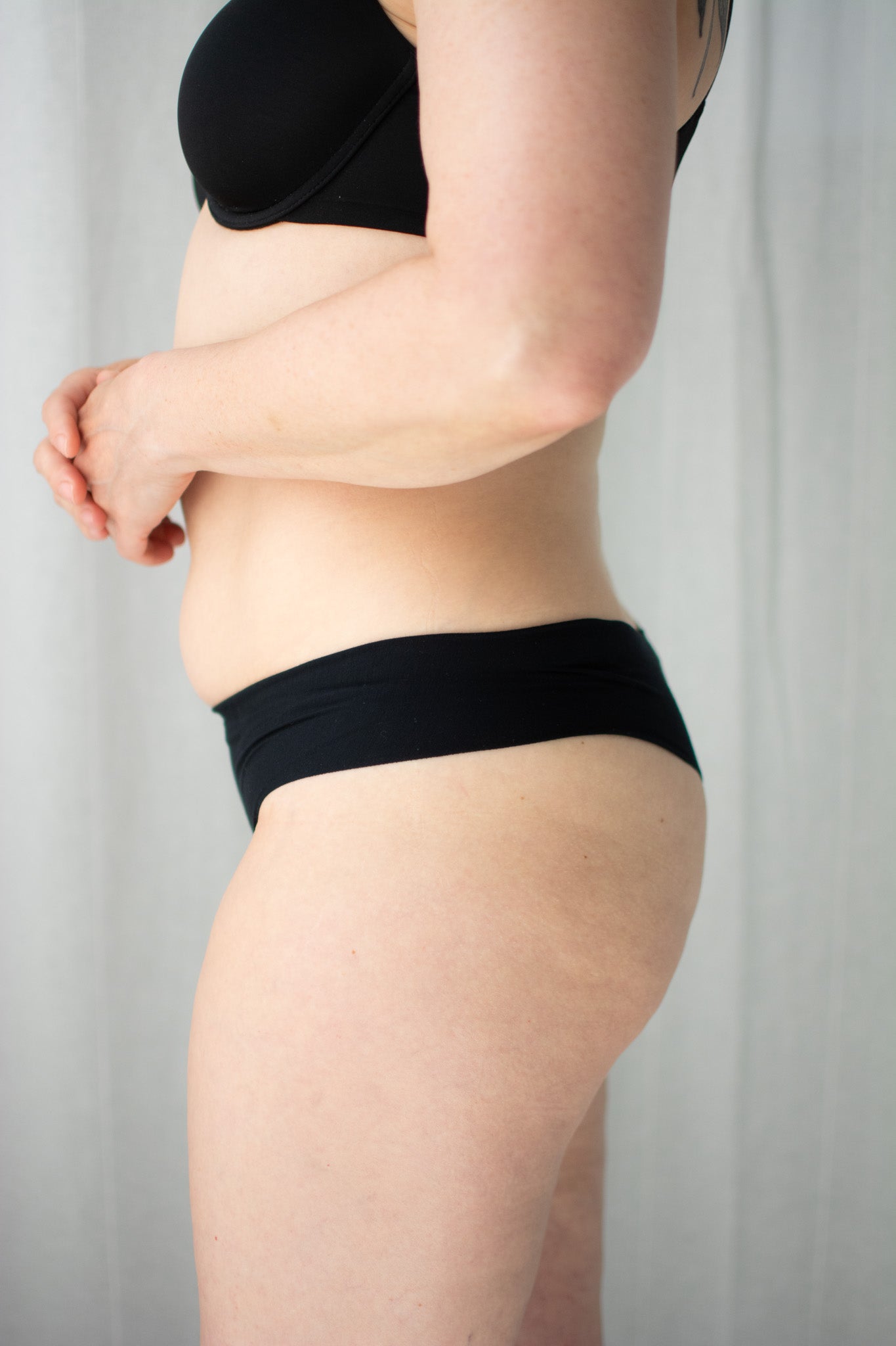 Person wearing black underwear against a neutral background