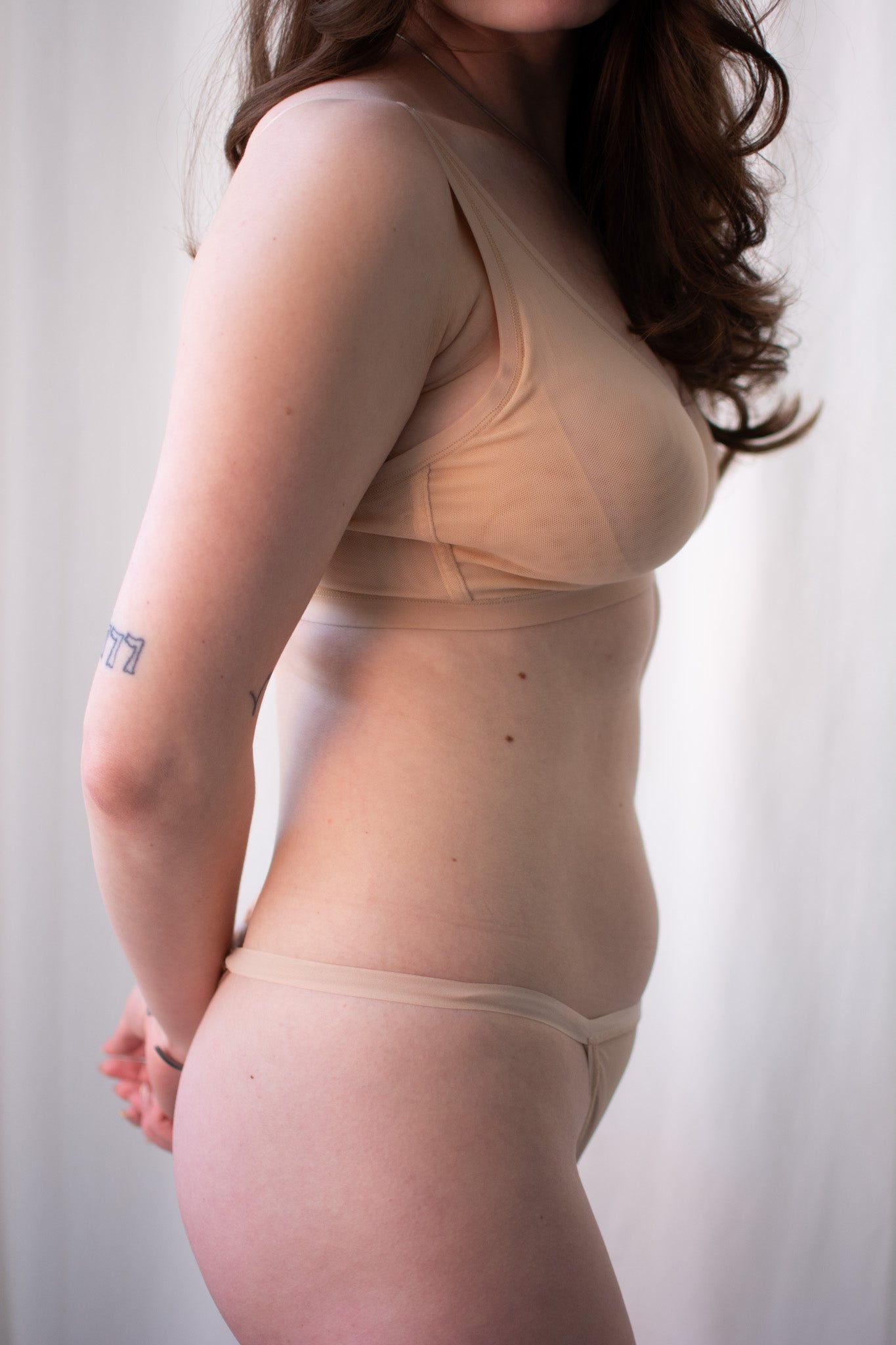 Woman wearing a beige shapewear garment against a plain background