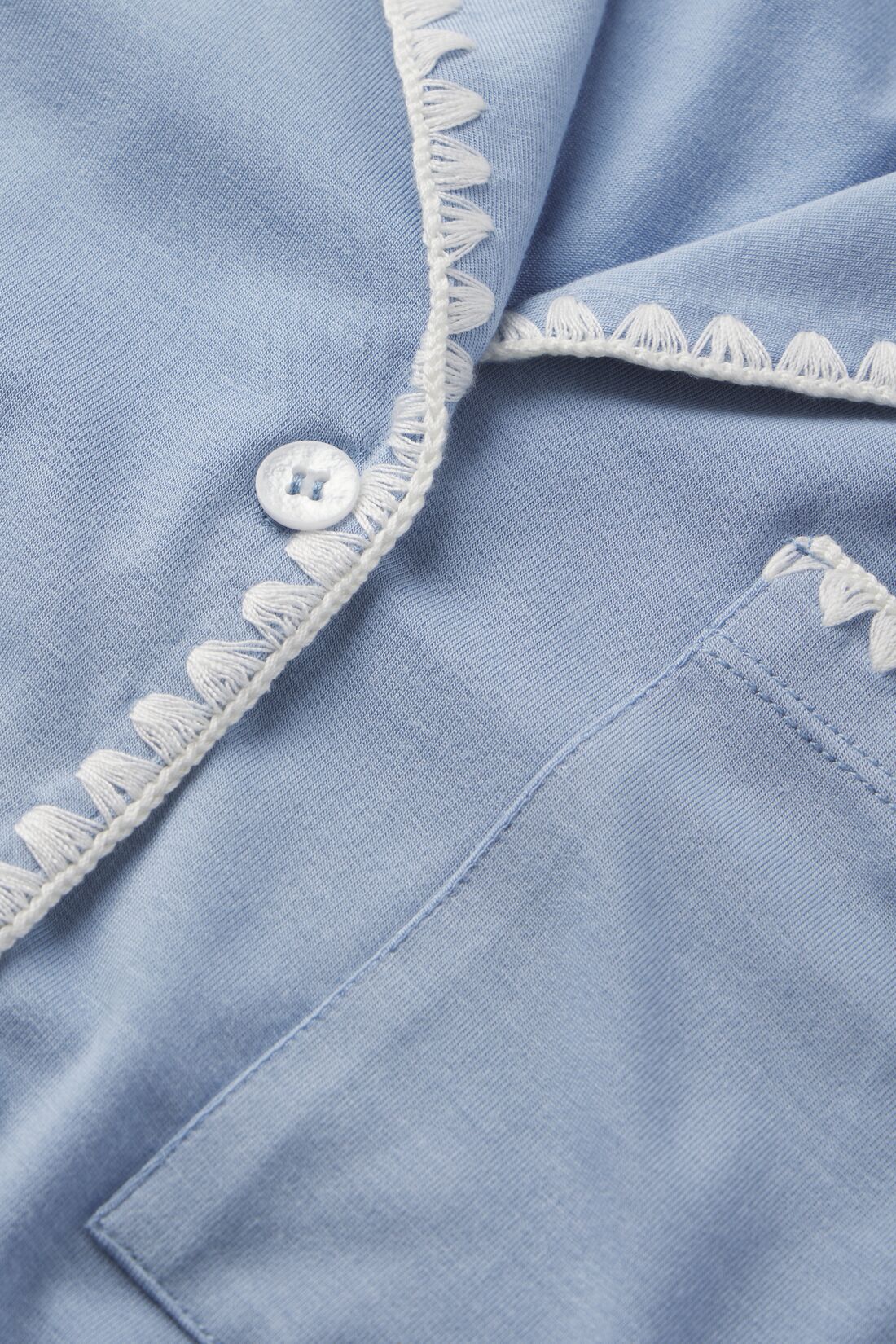 close up image of blue pajamas with white stitching and white buttons.