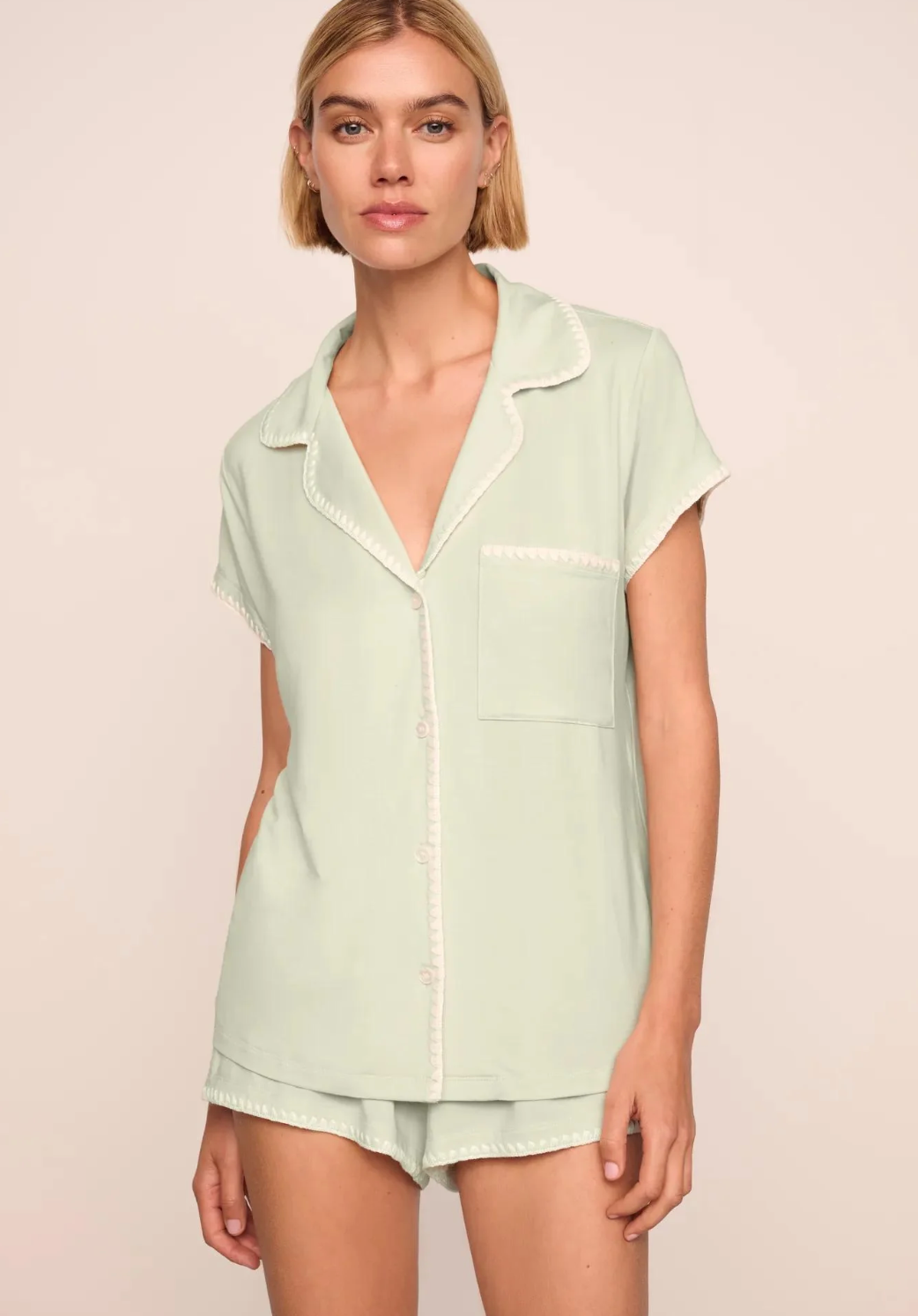 Woman wearing a light green pajama set against a beige background