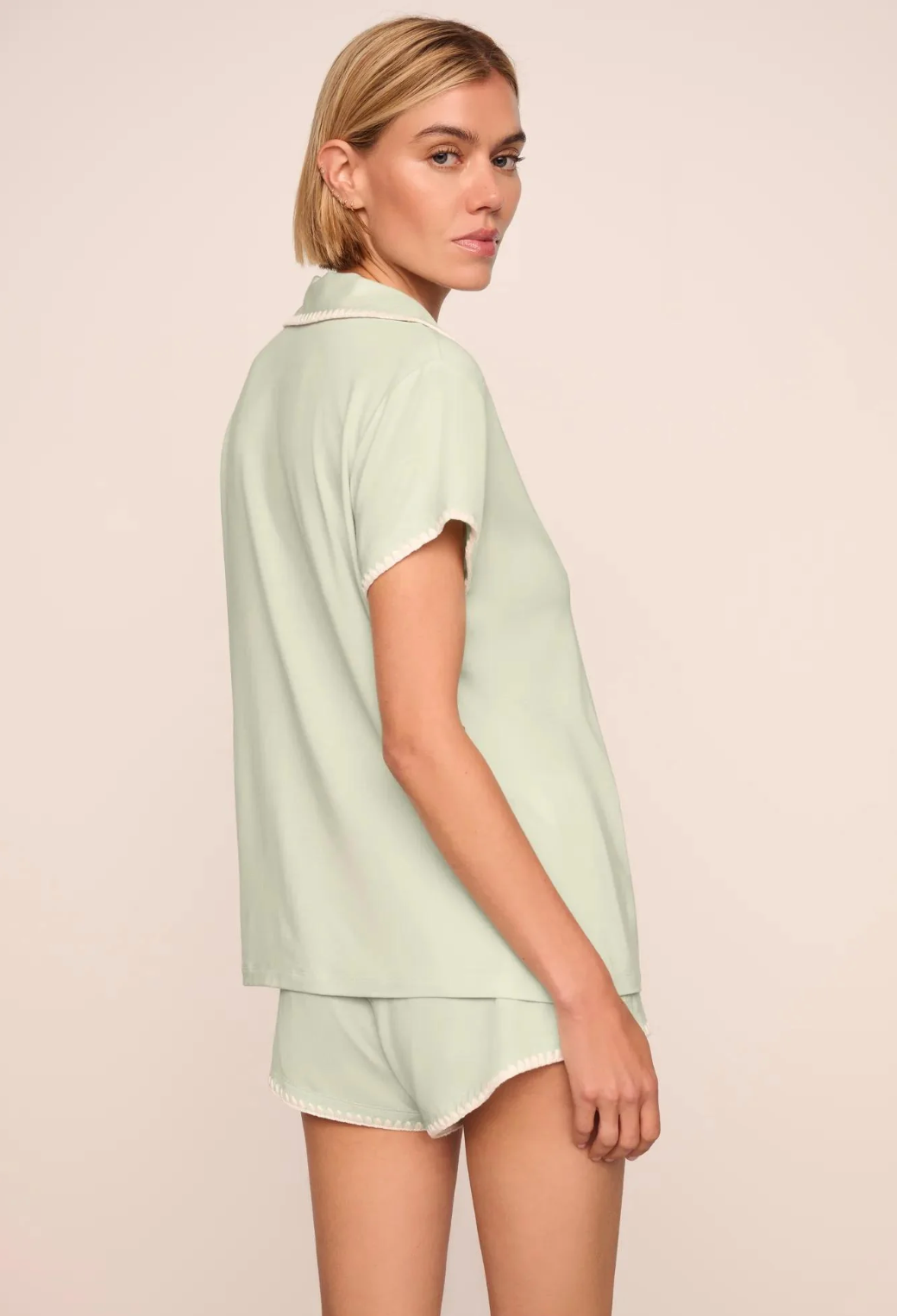 Woman wearing a light green shirt and shorts set on a beige background