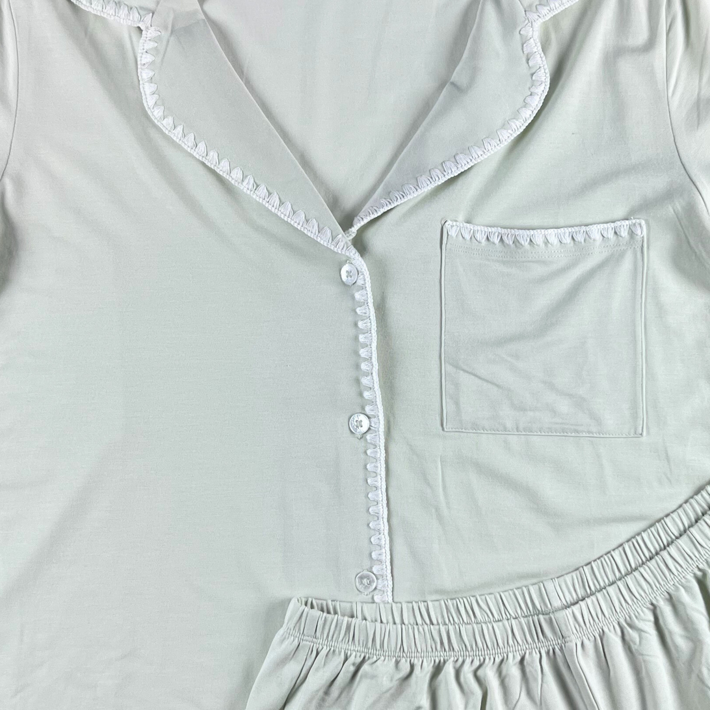 Light gray pajama top with lace trim and a pocket on a white background