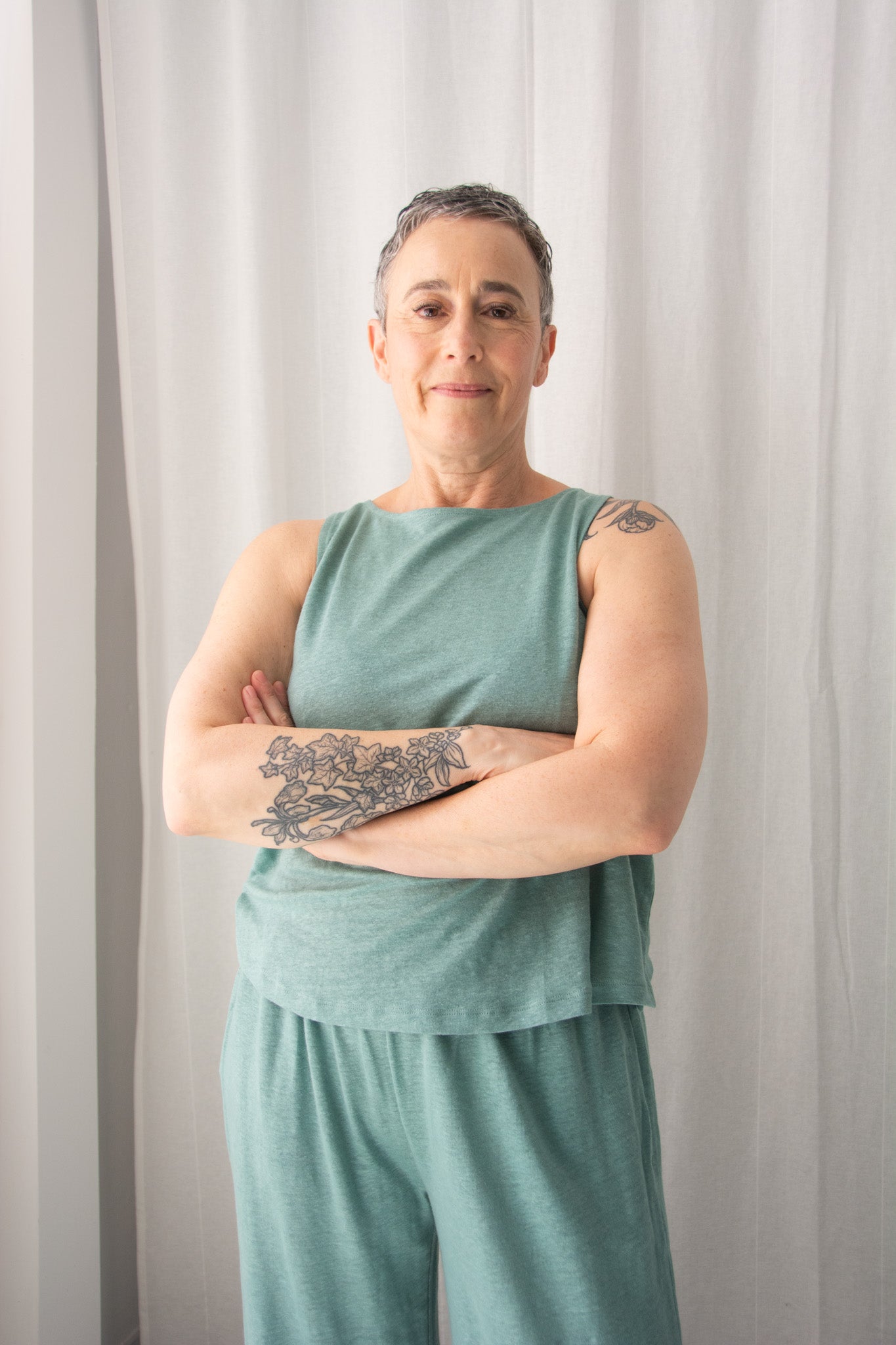 Person wearing a green sleeveless top and shorts against a plain background