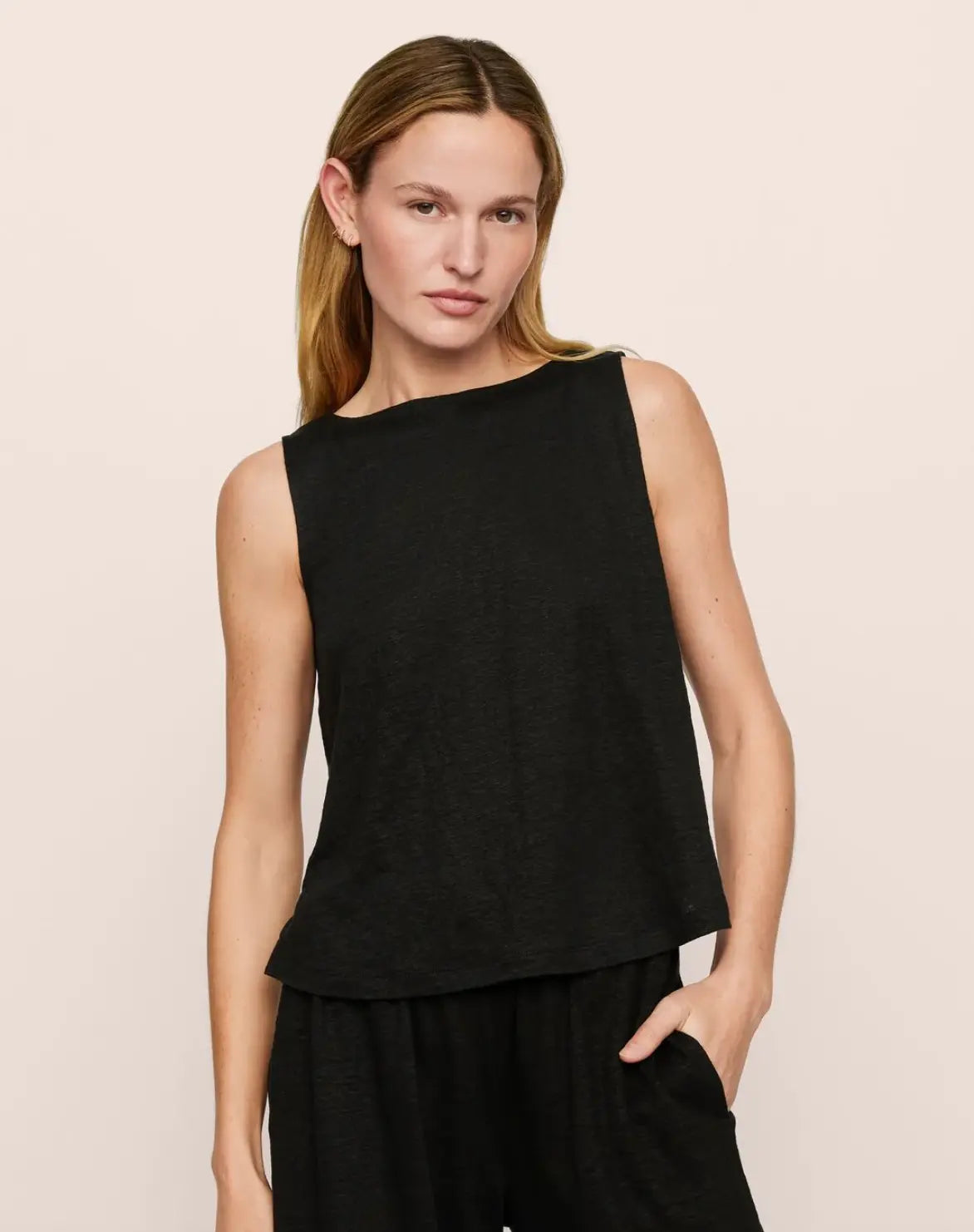 Woman wearing a black sleeveless top against a beige background