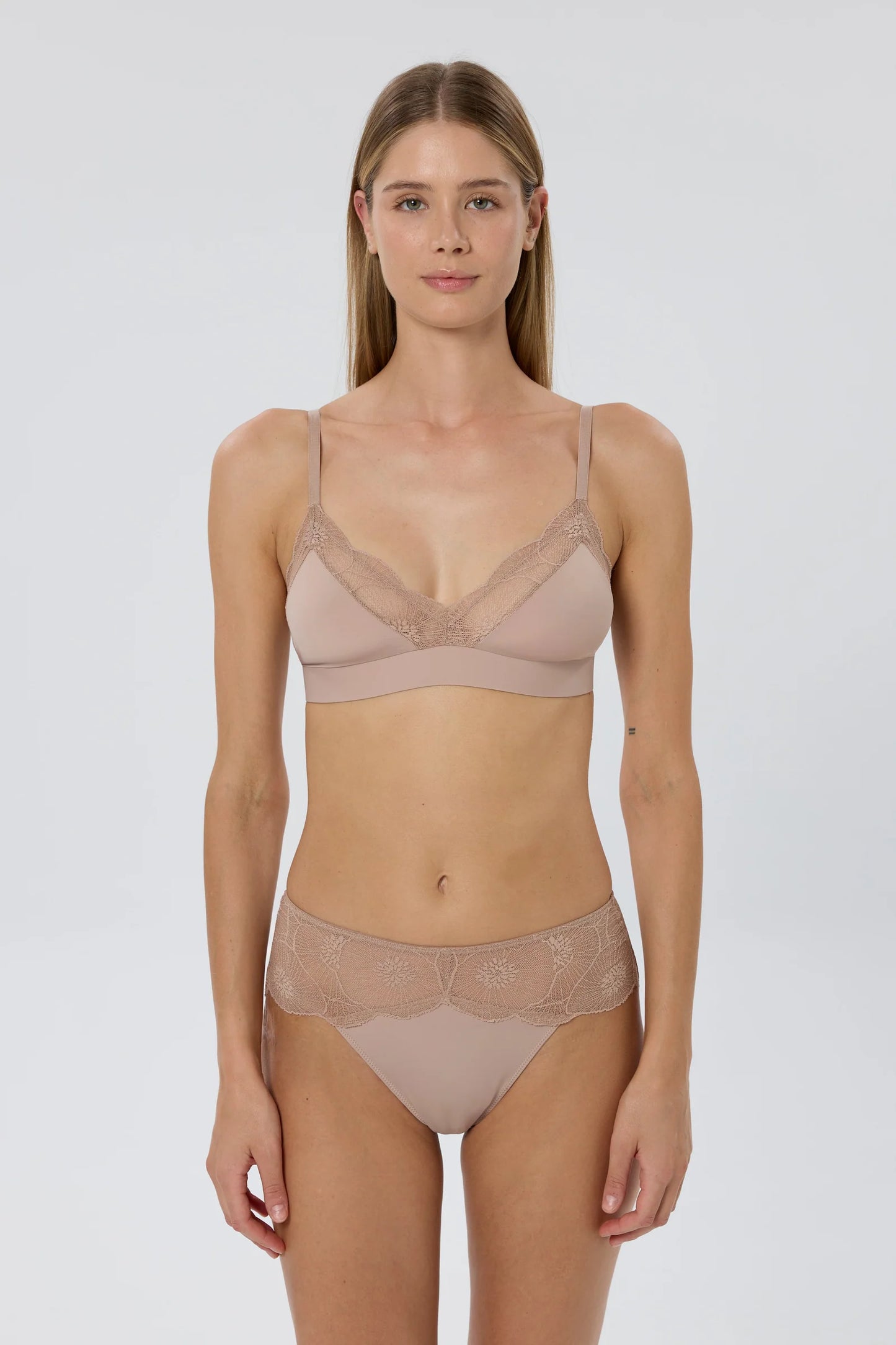Woman wearing a beige bra and panties set on a white background