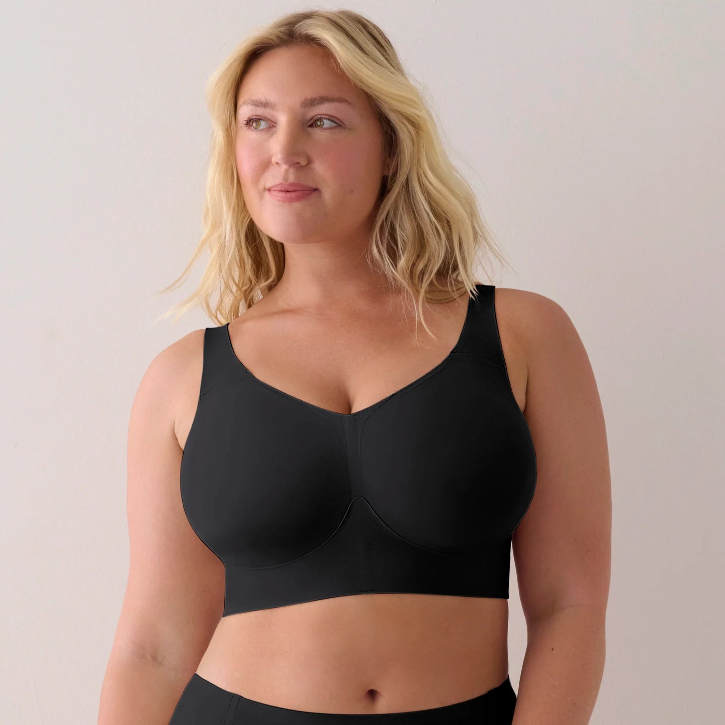 Woman wearing a black full cup bra against a plain background