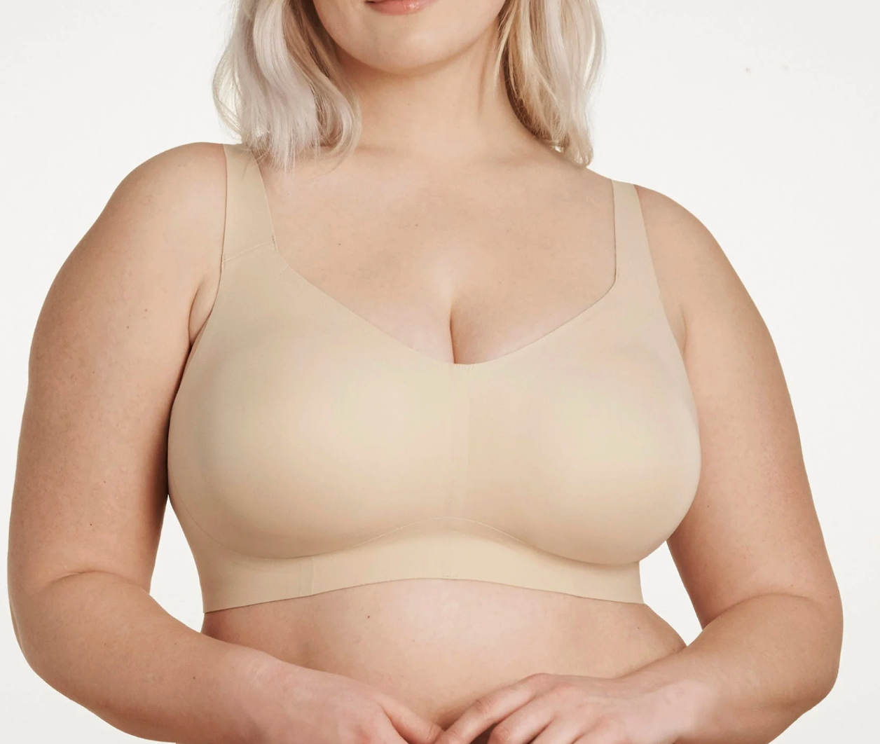 Woman wearing a beige bra on a plain background