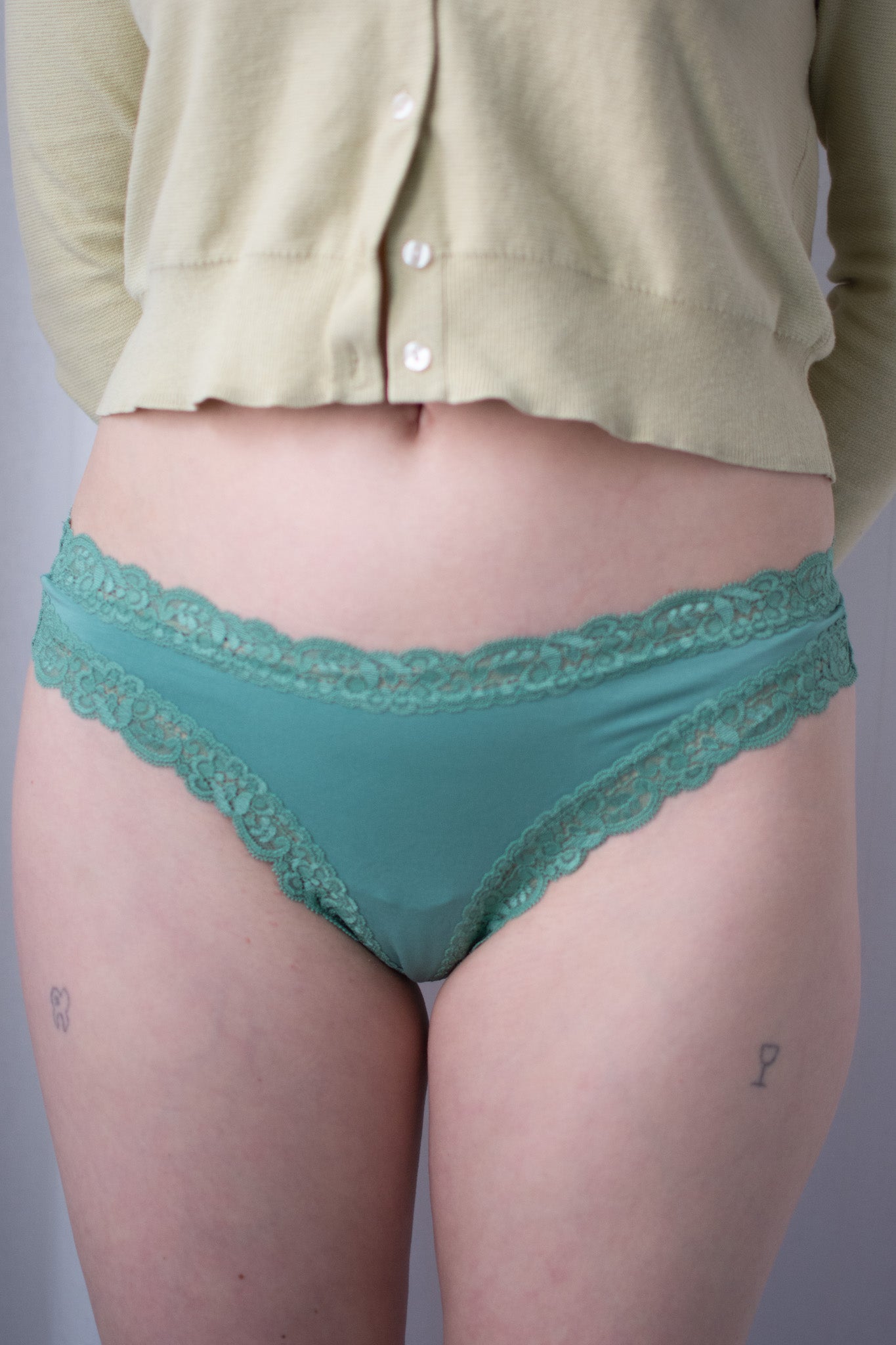 Teal lace underwear worn by a person against a plain background
