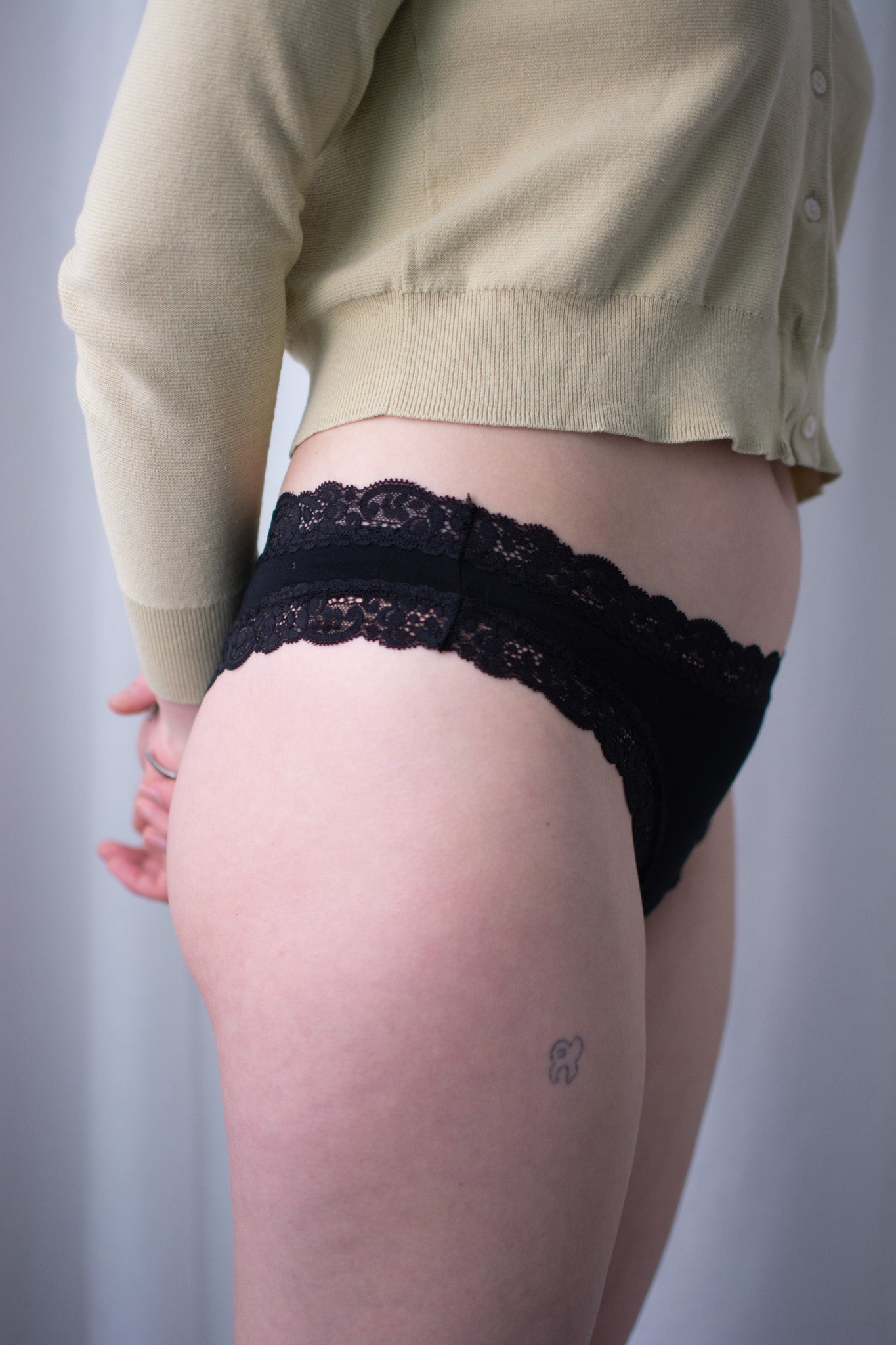 Person wearing black lace underwear with a plain background