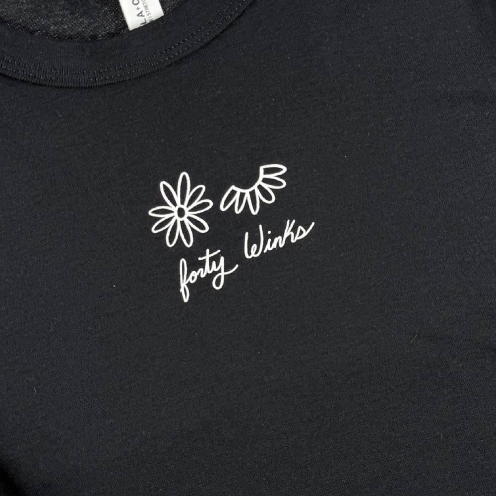 Black t-shirt with white floral design and 'forty winks' text on a plain background