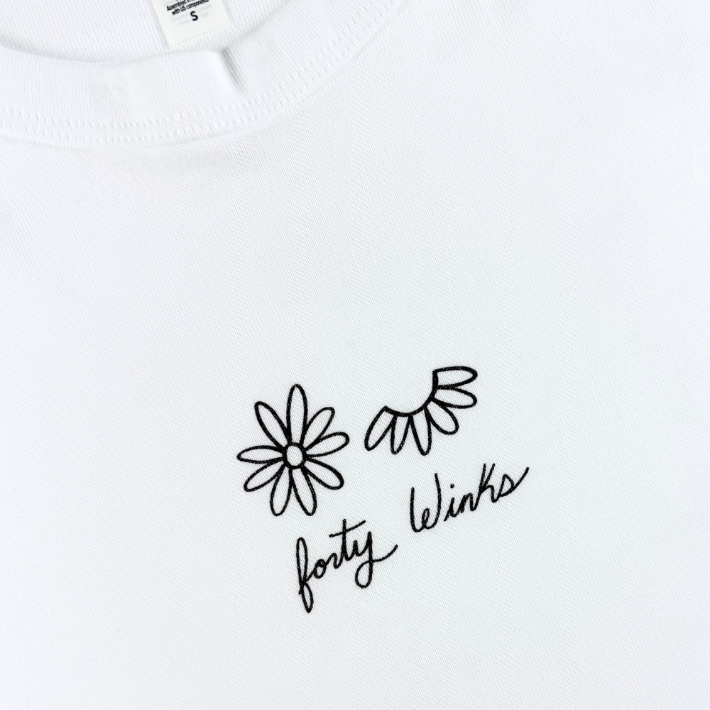 White shirt with black floral design and 'forty Winks' text on a white background