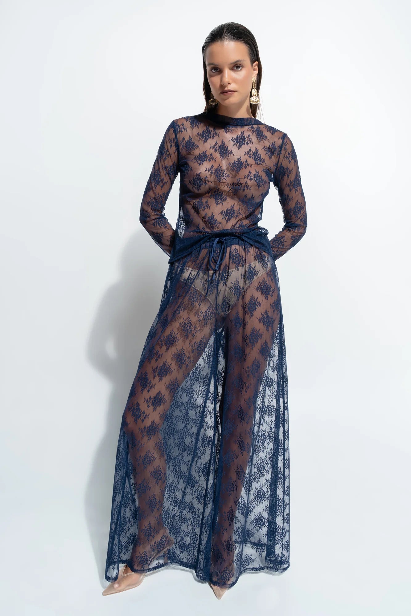 person wearing blue lace sheet pants and top against a white background.