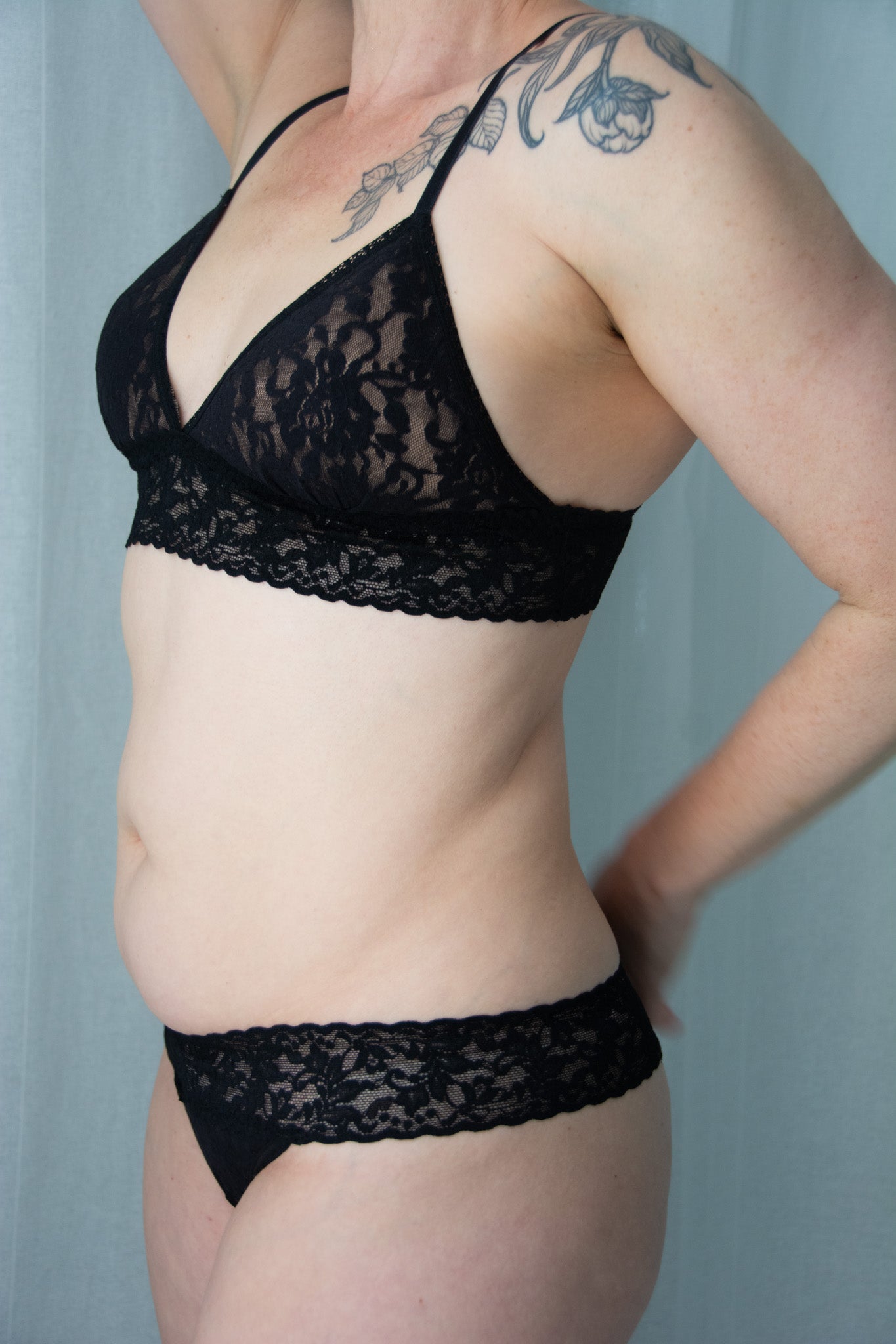 Person wearing a black lace bra and panties set against a plain background