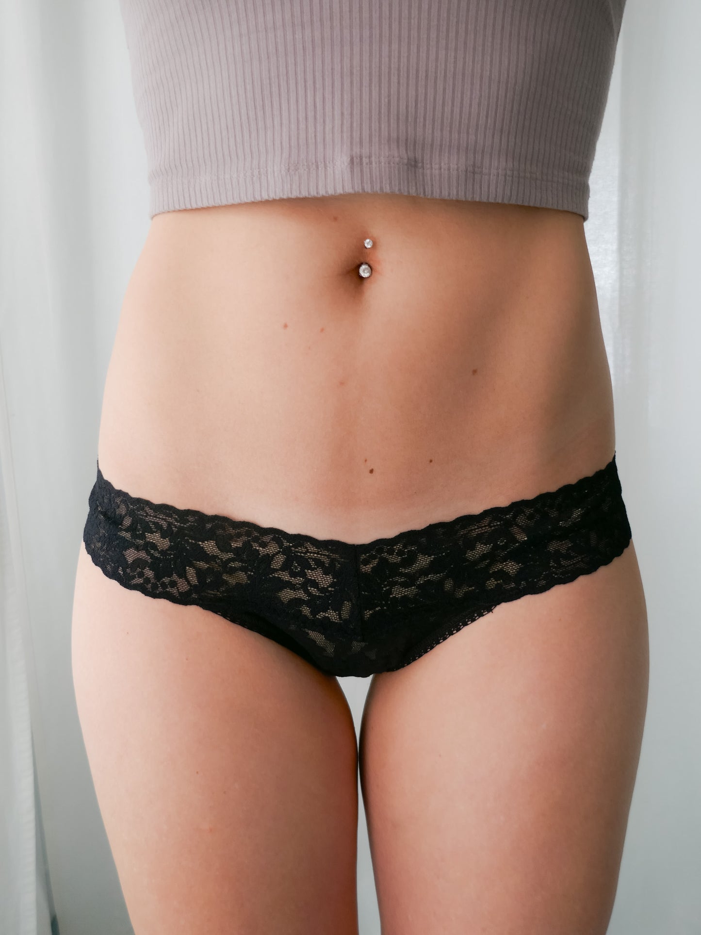 Person wearing black lace underwear against a neutral background