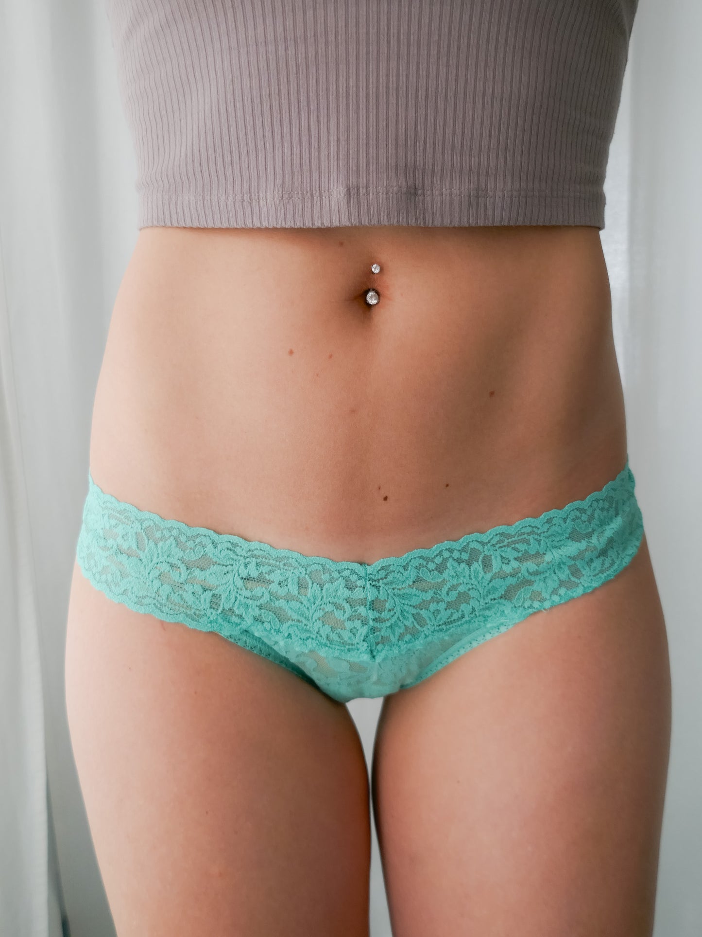 Person wearing teal lace underwear with a plain background