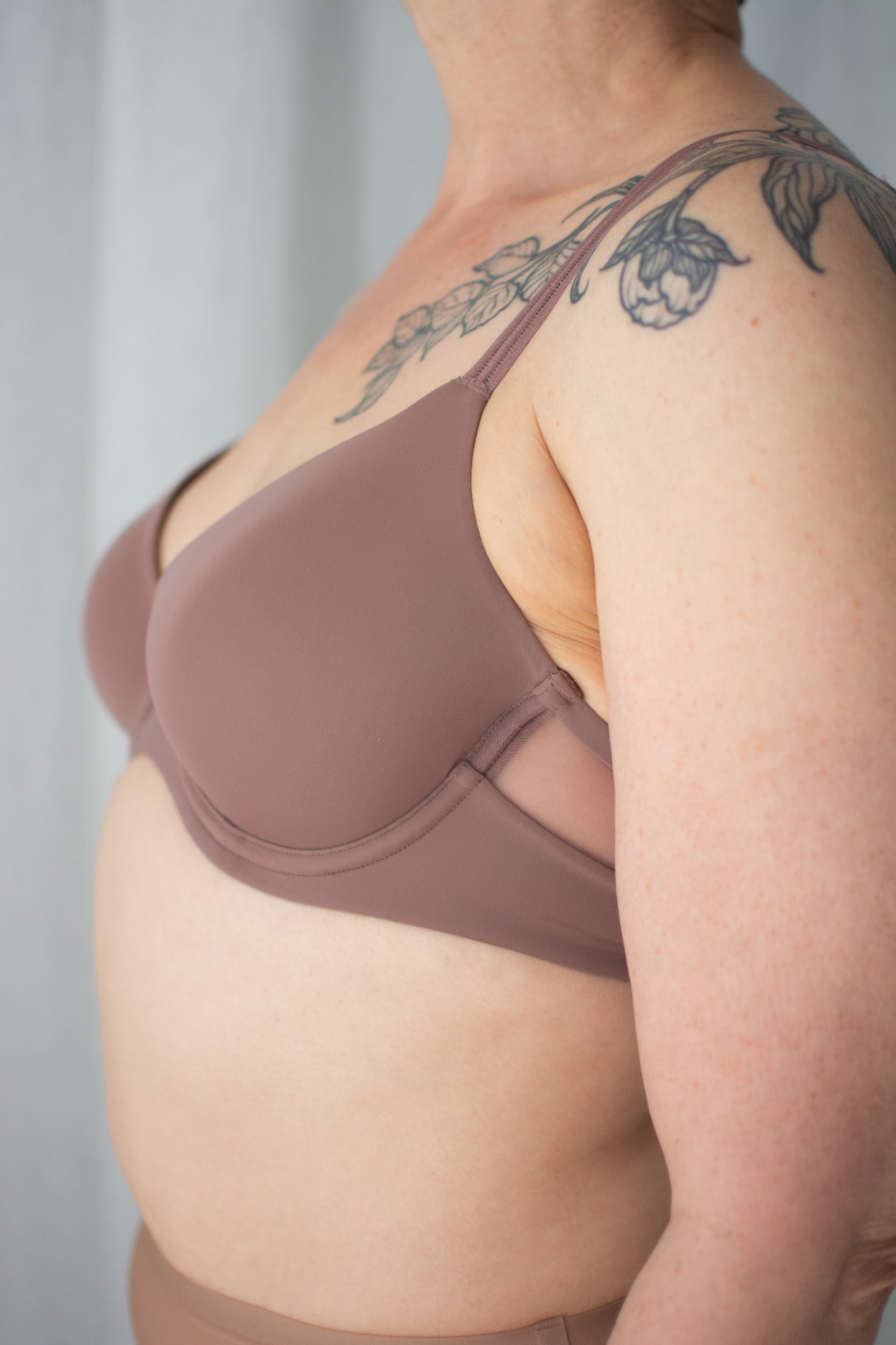 Brown bra worn by a person with visible tattoos on a neutral background