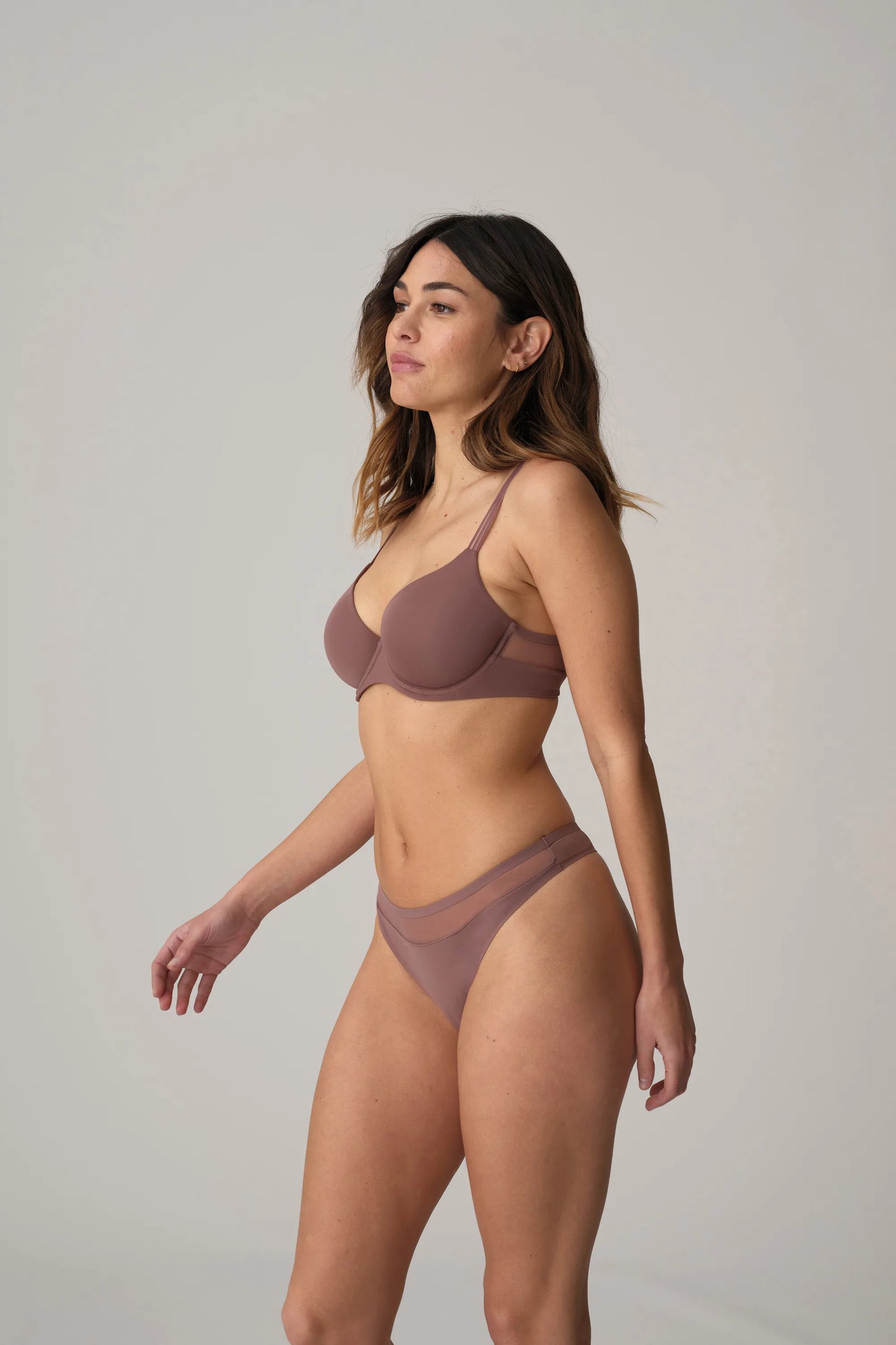Woman wearing mauve bra and underwear against white background.