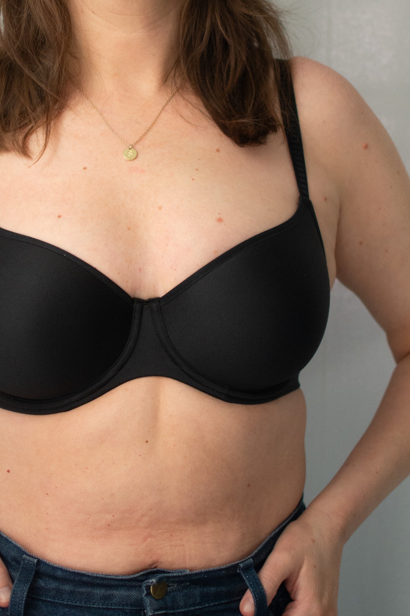Person wearing a black bra against a neutral background