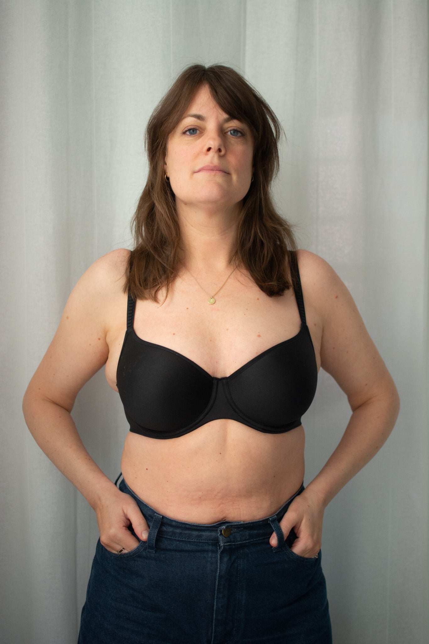 Woman wearing a black bra against a plain background