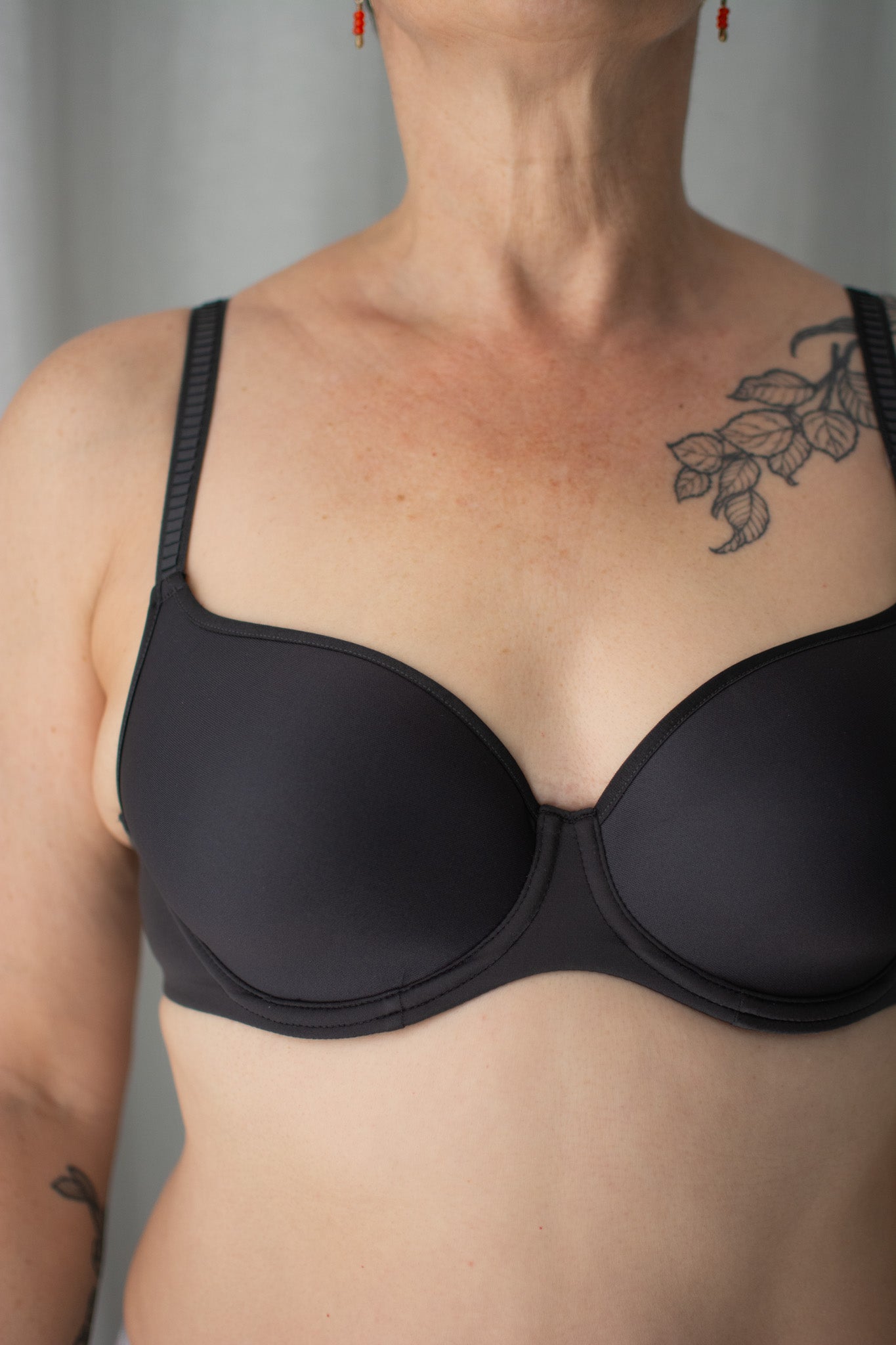 Person wearing a black bra against a neutral background