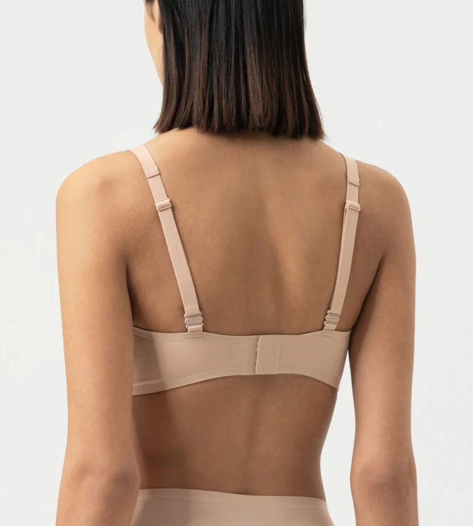 back of model wearing beige lingerie set against a white background.