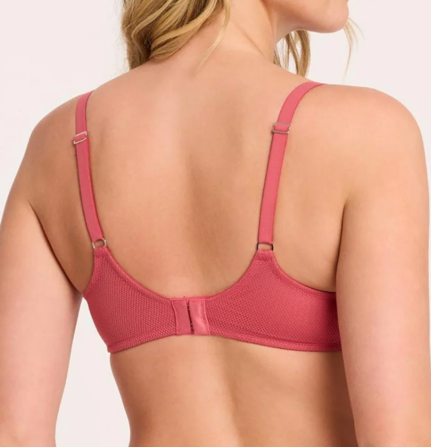Rear view of a woman wearing a dusty rose pink underwire bra with adjustable shoulder straps and a mesh back panel, set against a plain light background.