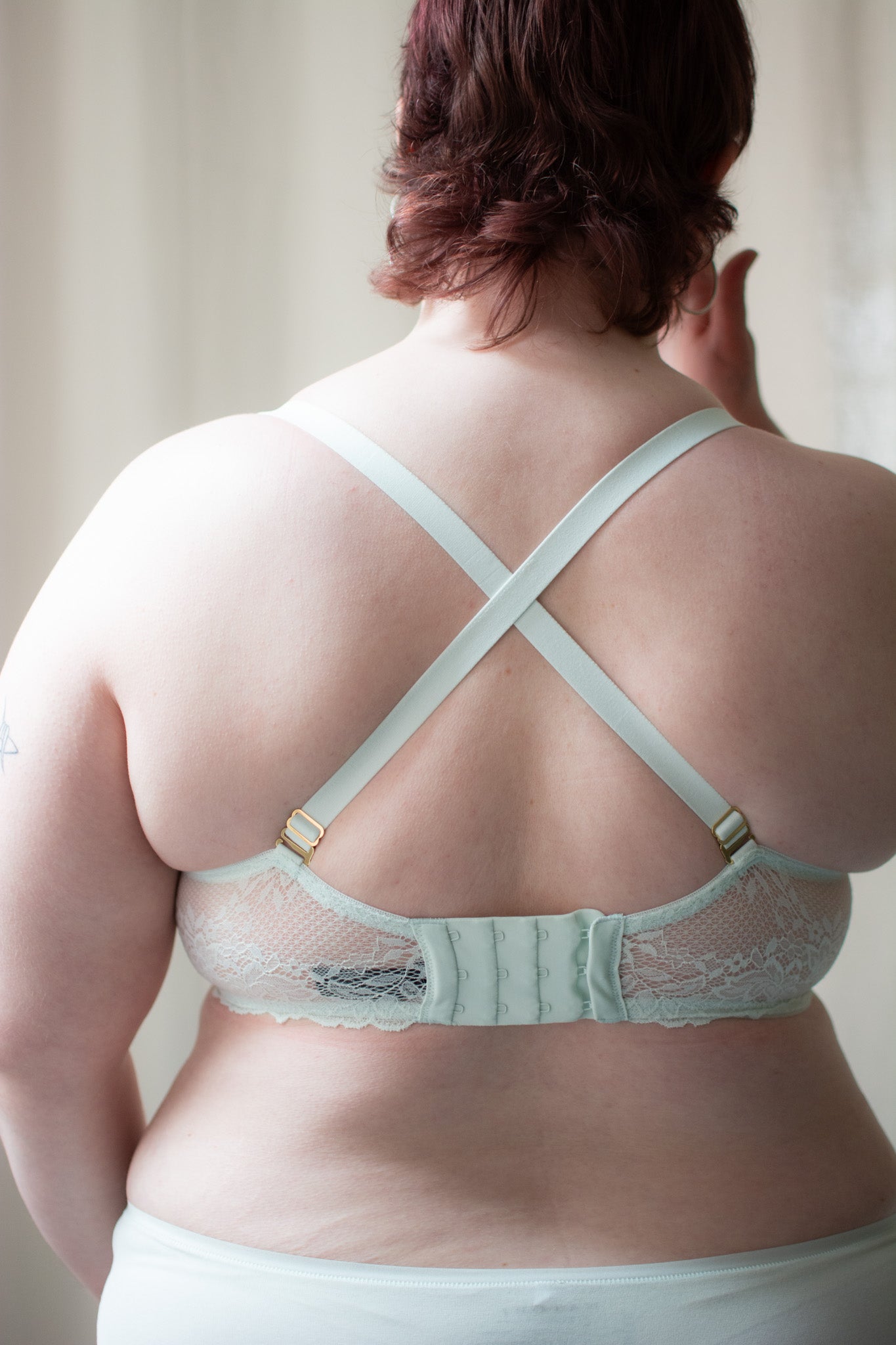 Person wearing mint lace bra against a neutral background.