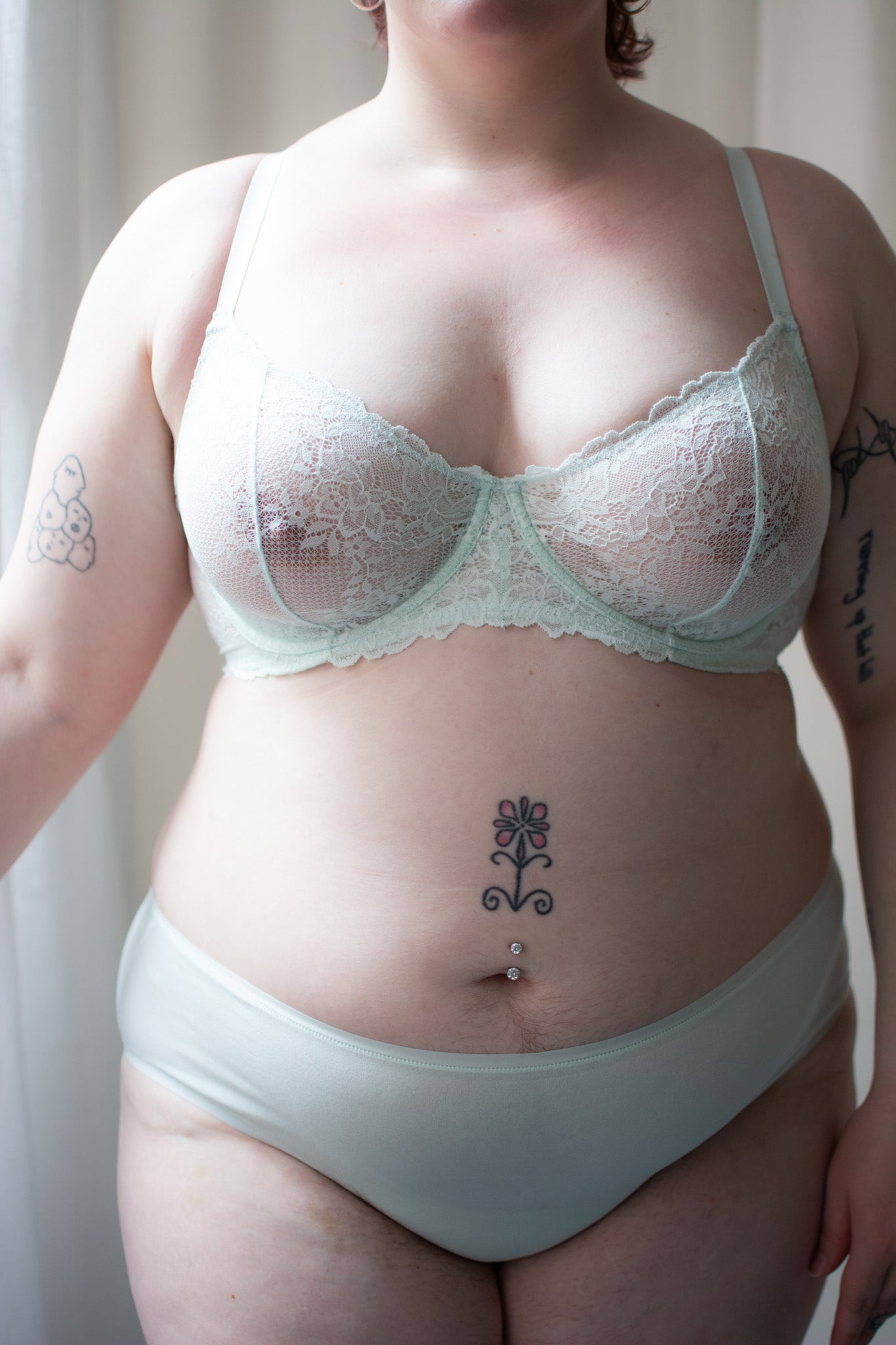 Person wearing mint lace bra against a neutral background.