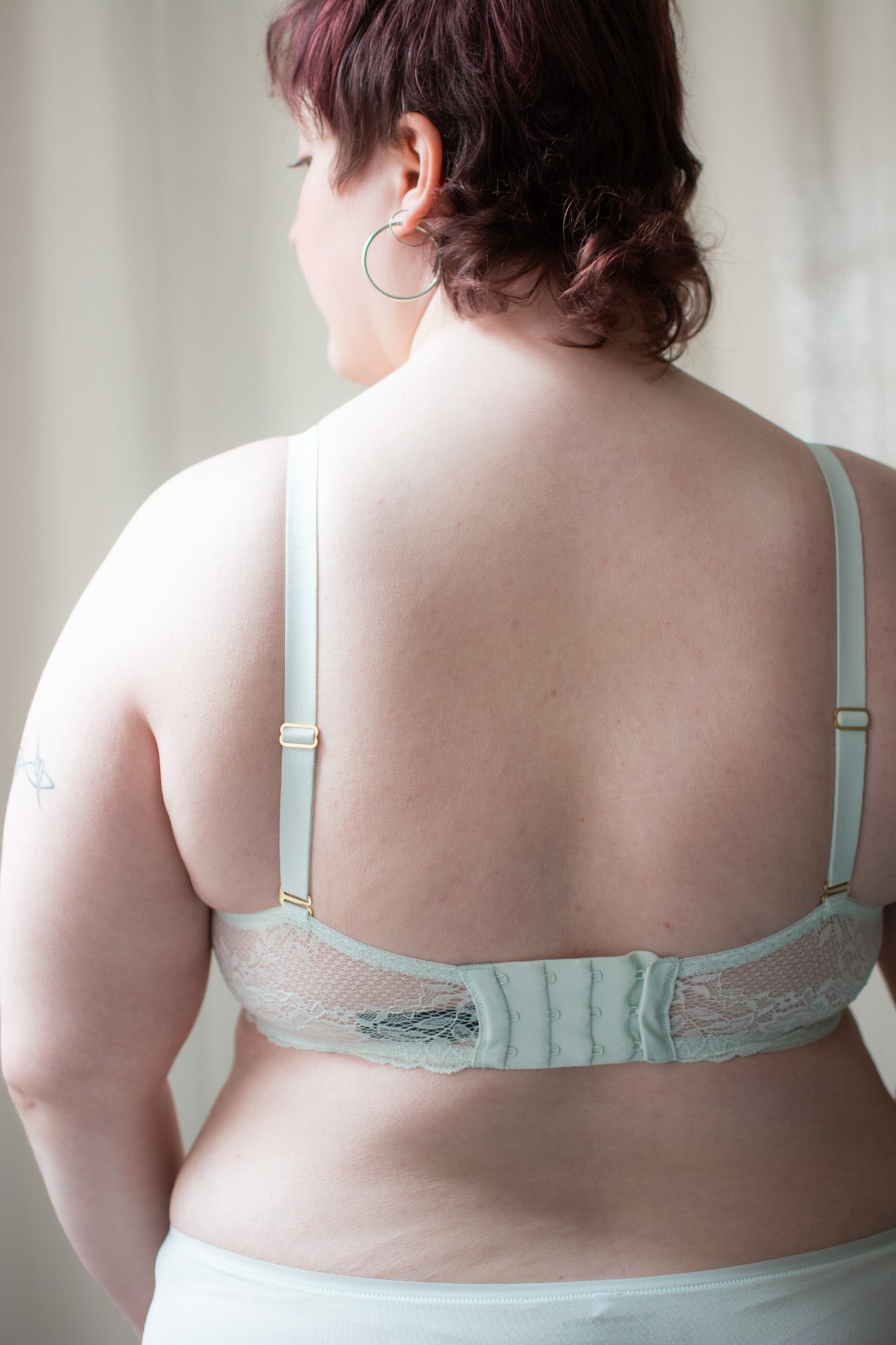 Person wearing mint lace bra against a neutral background.