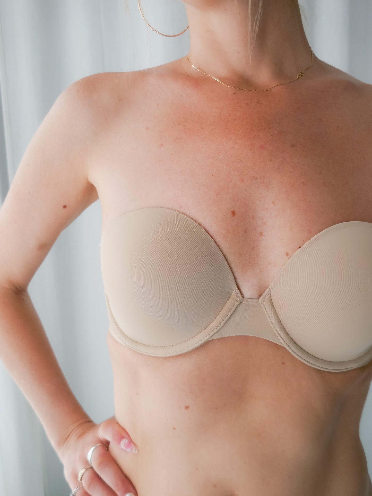 Beige strapless bra worn by a person against a neutral background