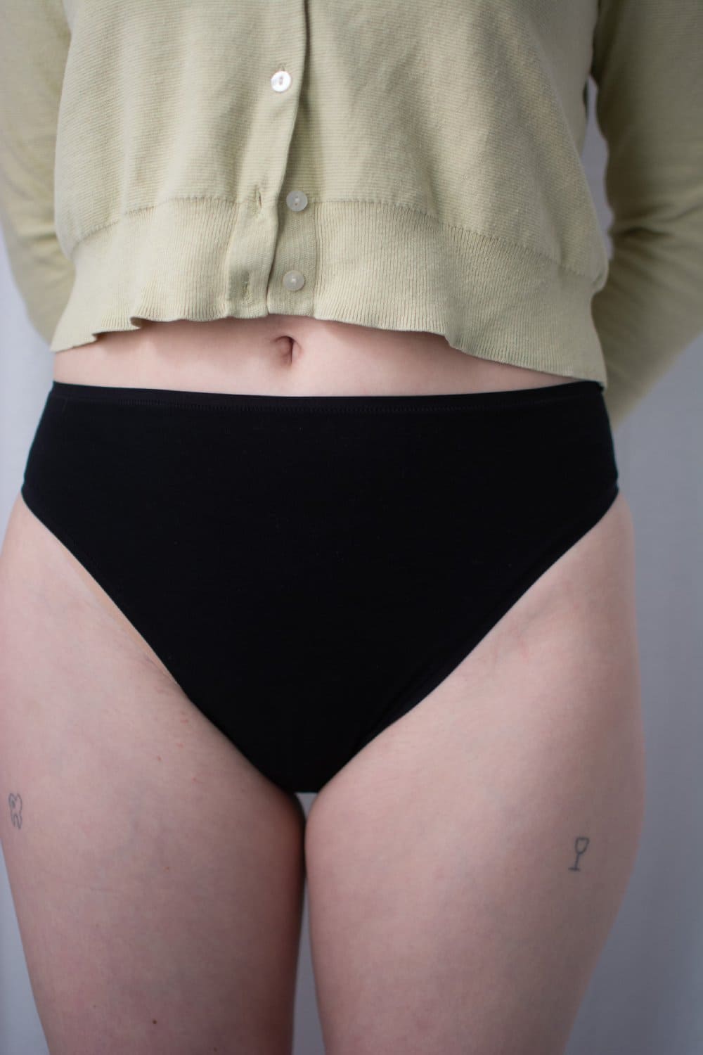 Natori bliss bare cotton high cut brief in black, front view on a model, close-up.