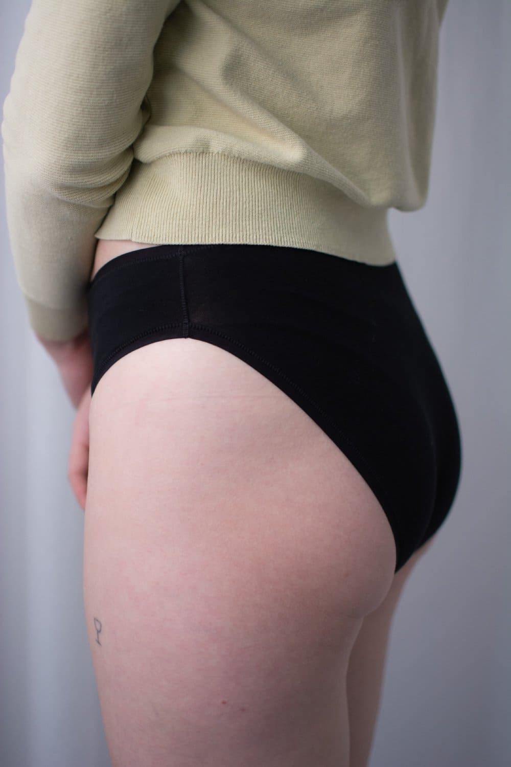 Natori bliss bare cotton high cut brief in black, side view on a model, close-up.