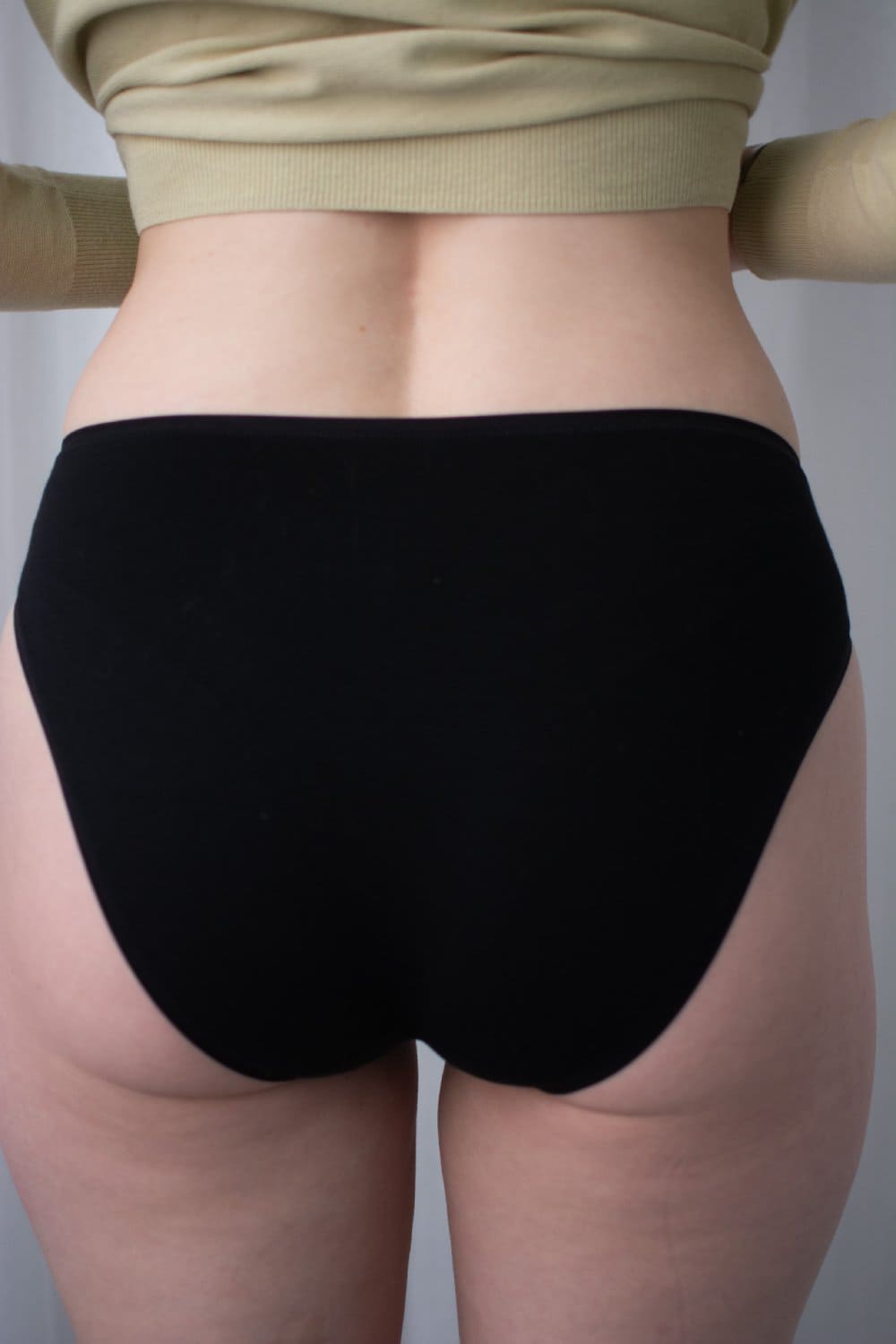 Natori bliss bare cotton high cut brief in black, side view on a model, close-up.